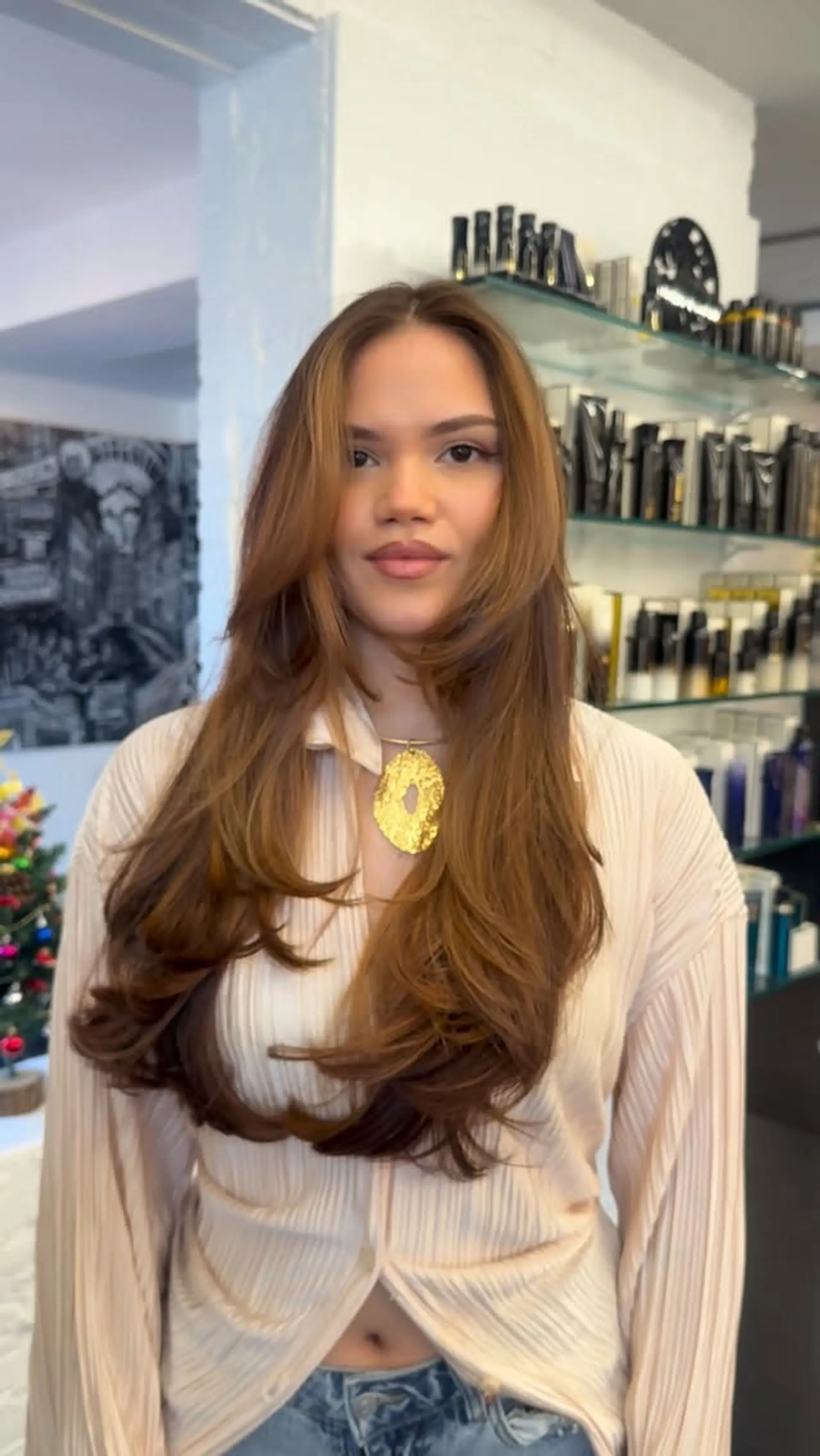 Long, voluminous caramel brown hair styled into a bouncy blowout with face-framing layers. 1