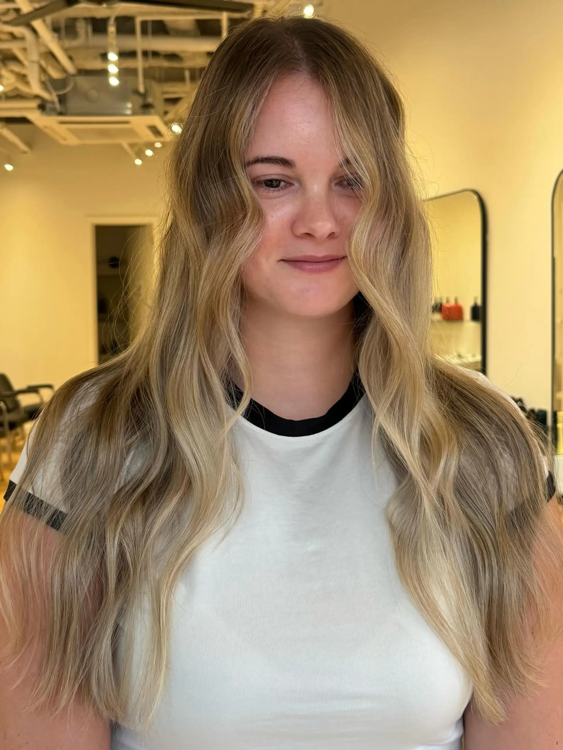 Long soft wavy hair with a seamless butter blonde balayage and subtle face-framing layers. 1