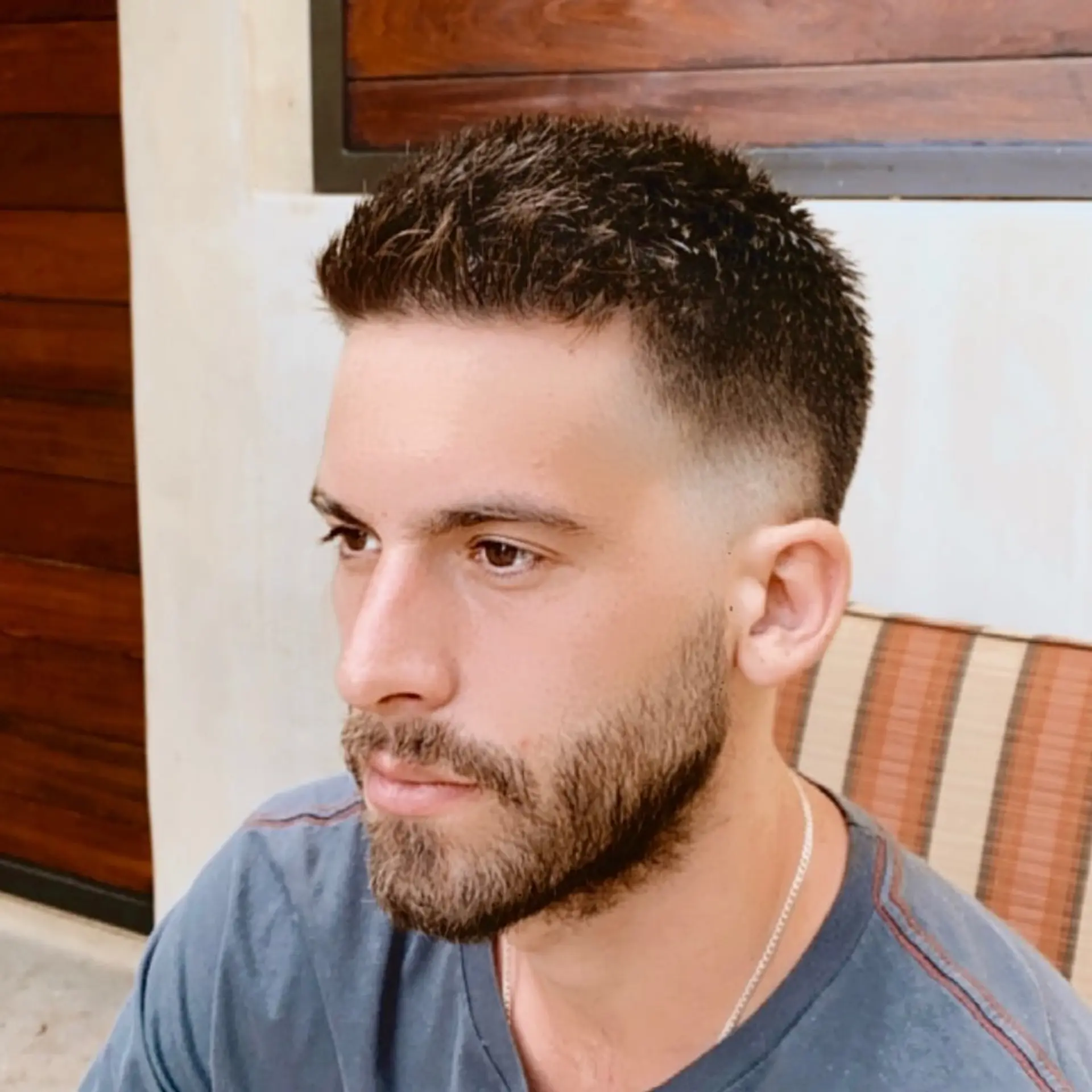 A short men's crop haircut with textured styling on top and a smooth low-to-mid fade on the sides. 1