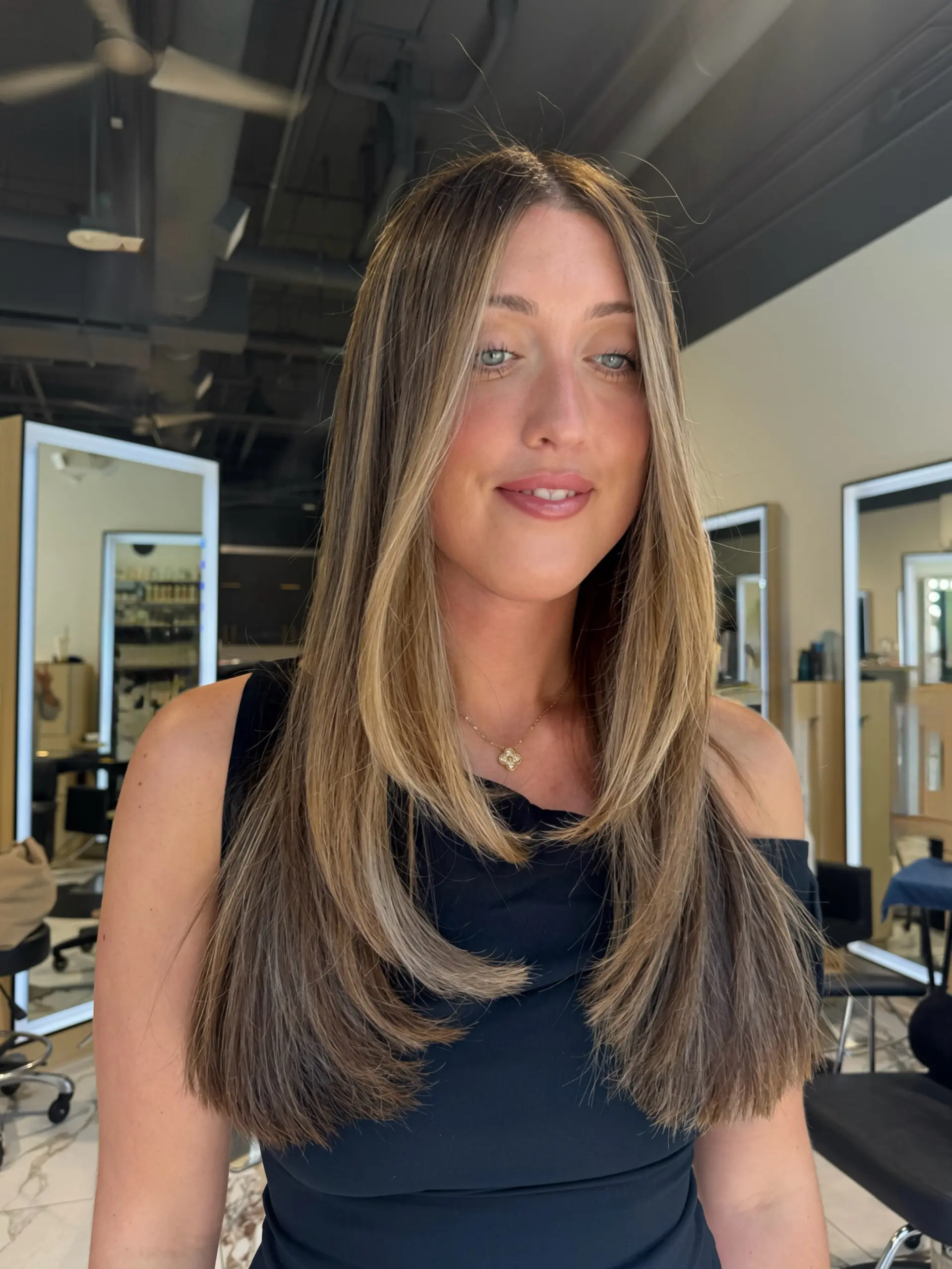 Straight, blow-dried long hair styled with cascading layers and soft face-framing pieces with warm dimensional highlights. 1