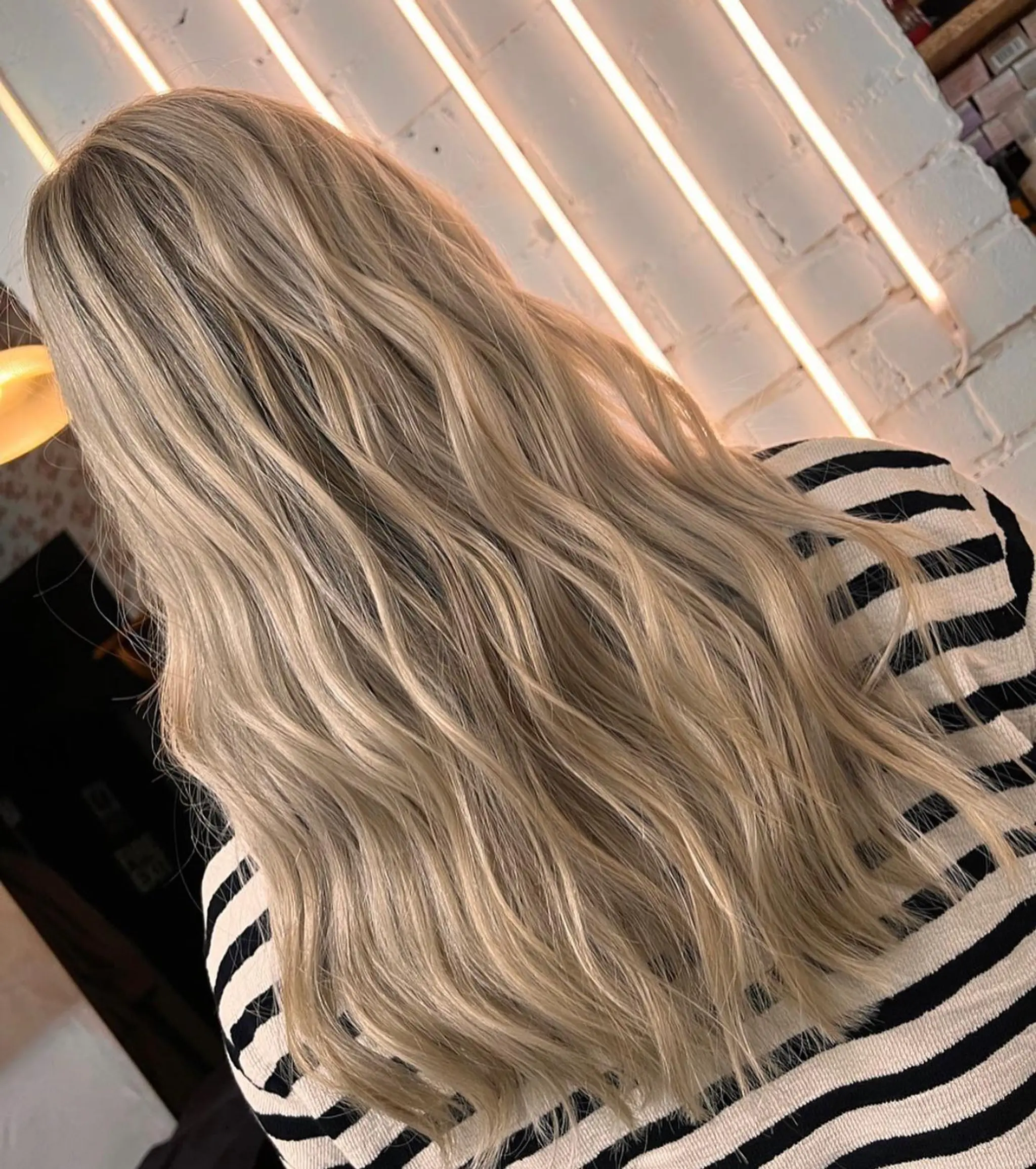 Very long, wavy blonde hair cascading down the back with gentle, natural waves, giving a carefree and elegant look.