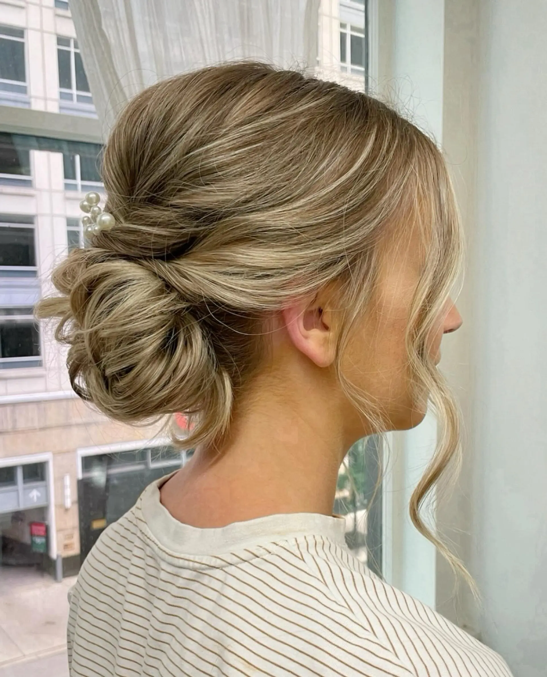 A chic and classic updo featuring a low bun with loose wavy strands. 1