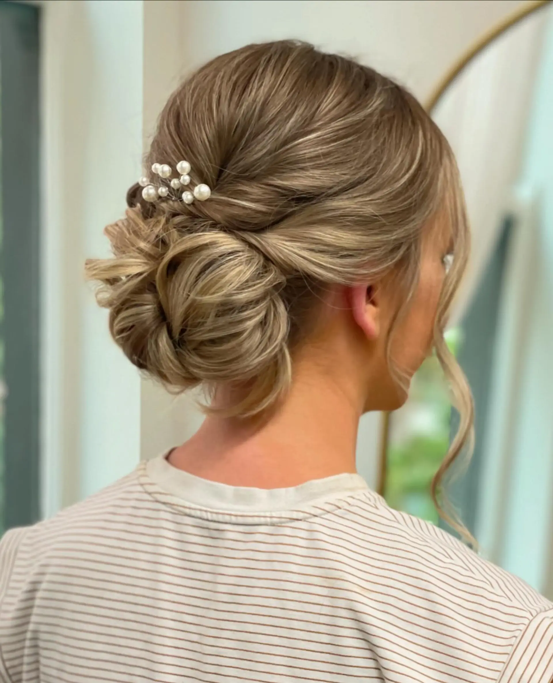 A chic and classic updo featuring a low bun with loose wavy strands. 3