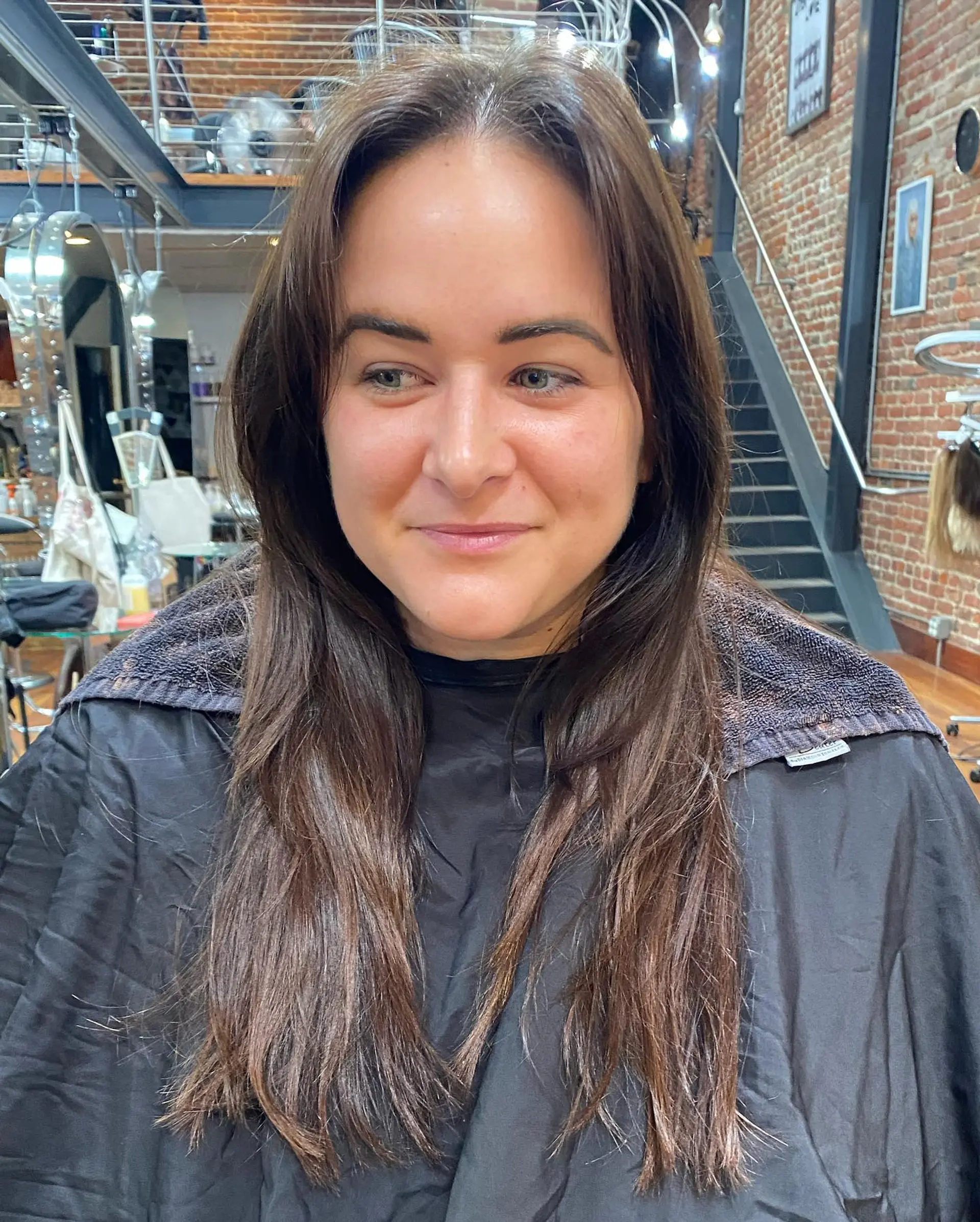 Long brunette hair styled straight with natural movement, parted in the center with soft face-framing layers. 1