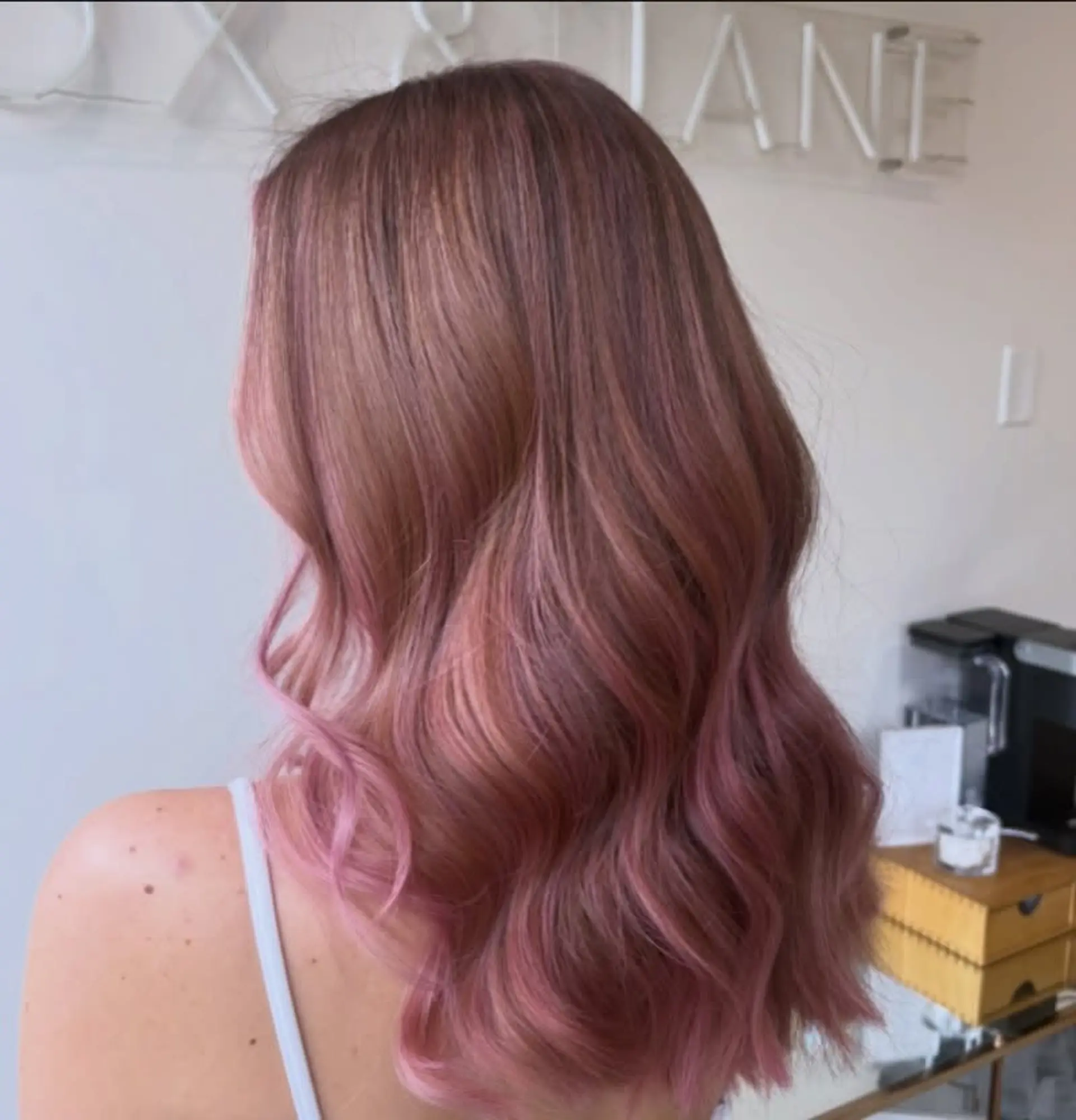 Long hair styled in soft, cascading waves colored in a delicate baby pink and rose gold tone. 1