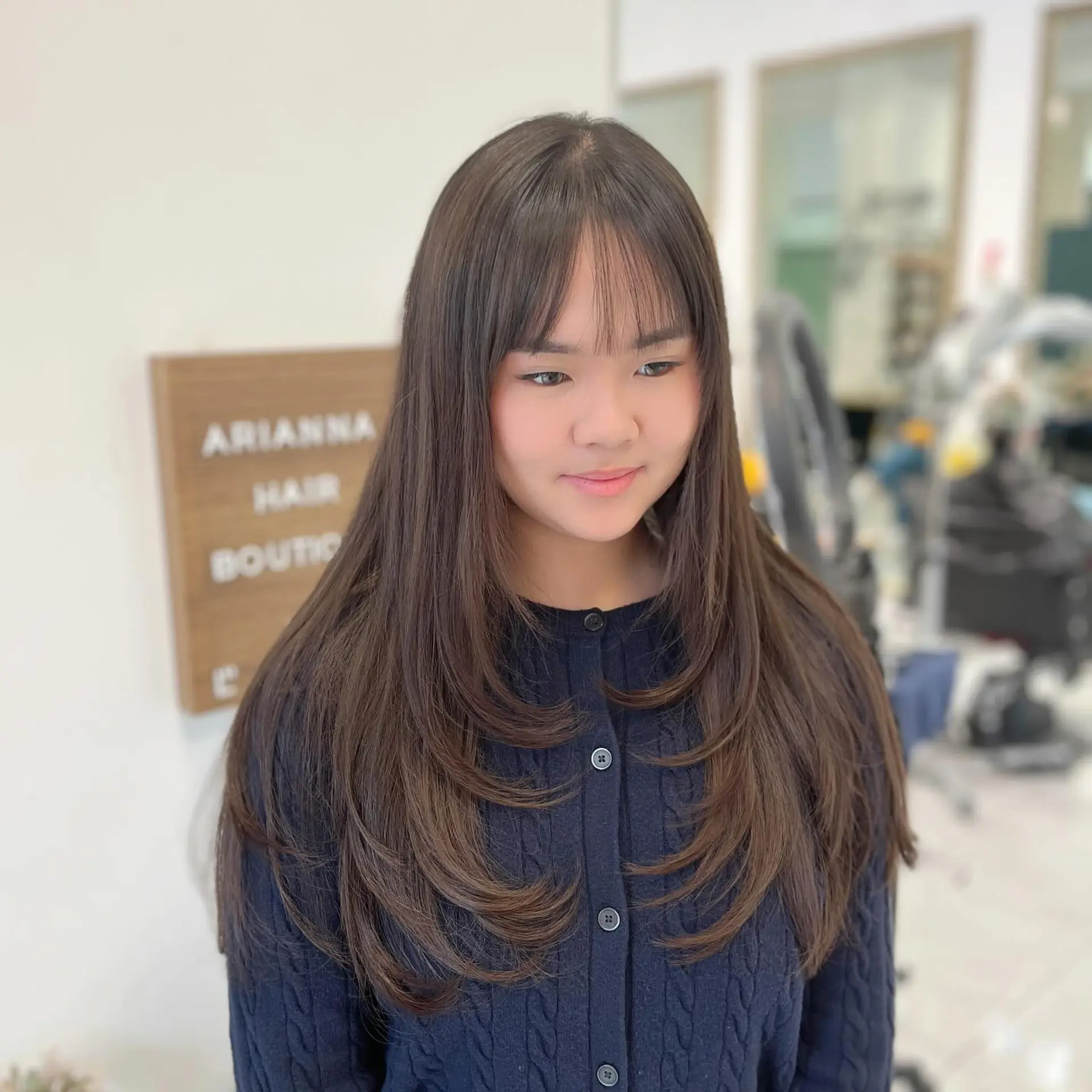 Long dark brown layered haircut featuring soft inward C-curls and wispy, see-through front bangs. 1