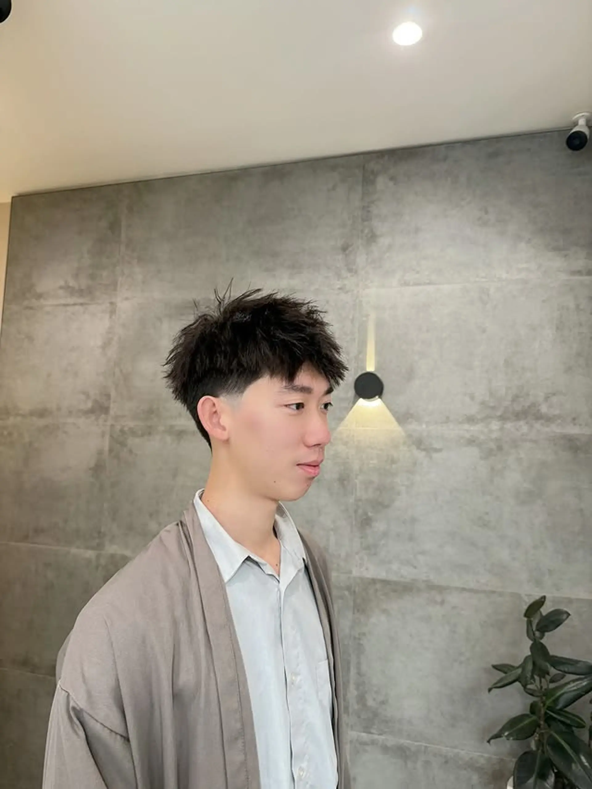 A short, textured hairstyle with a taper fade. 1