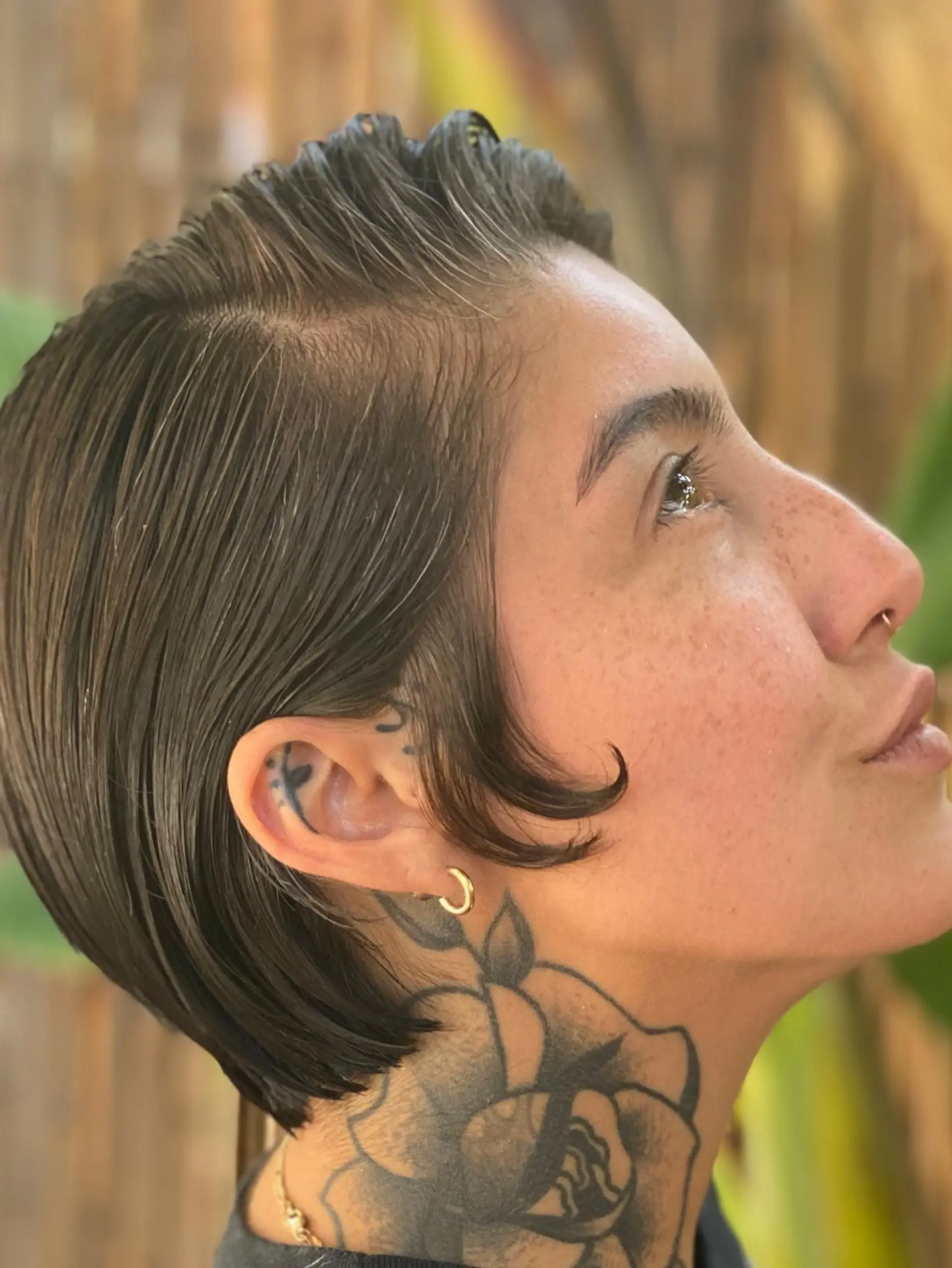 A sleek short crop cut with a side part and a sculpted curl at the temple. 1