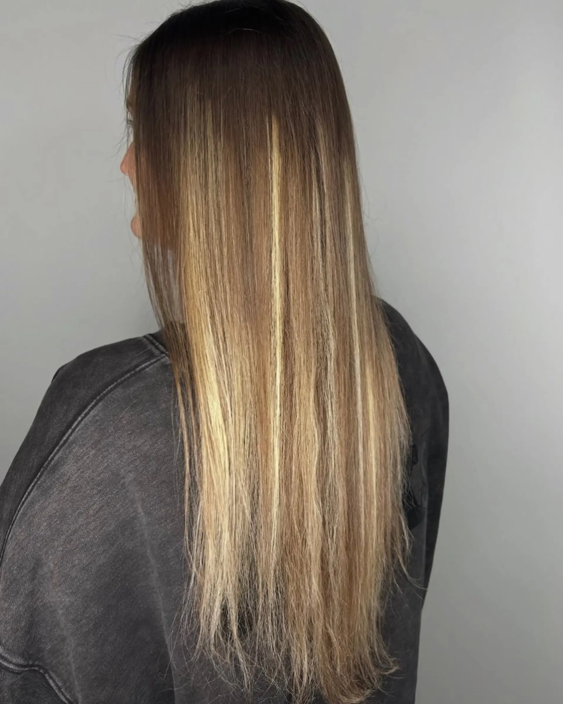 Long, smooth straight hair featuring a brunette base with bright blonde balayage highlights through the mid-lengths and ends. 1