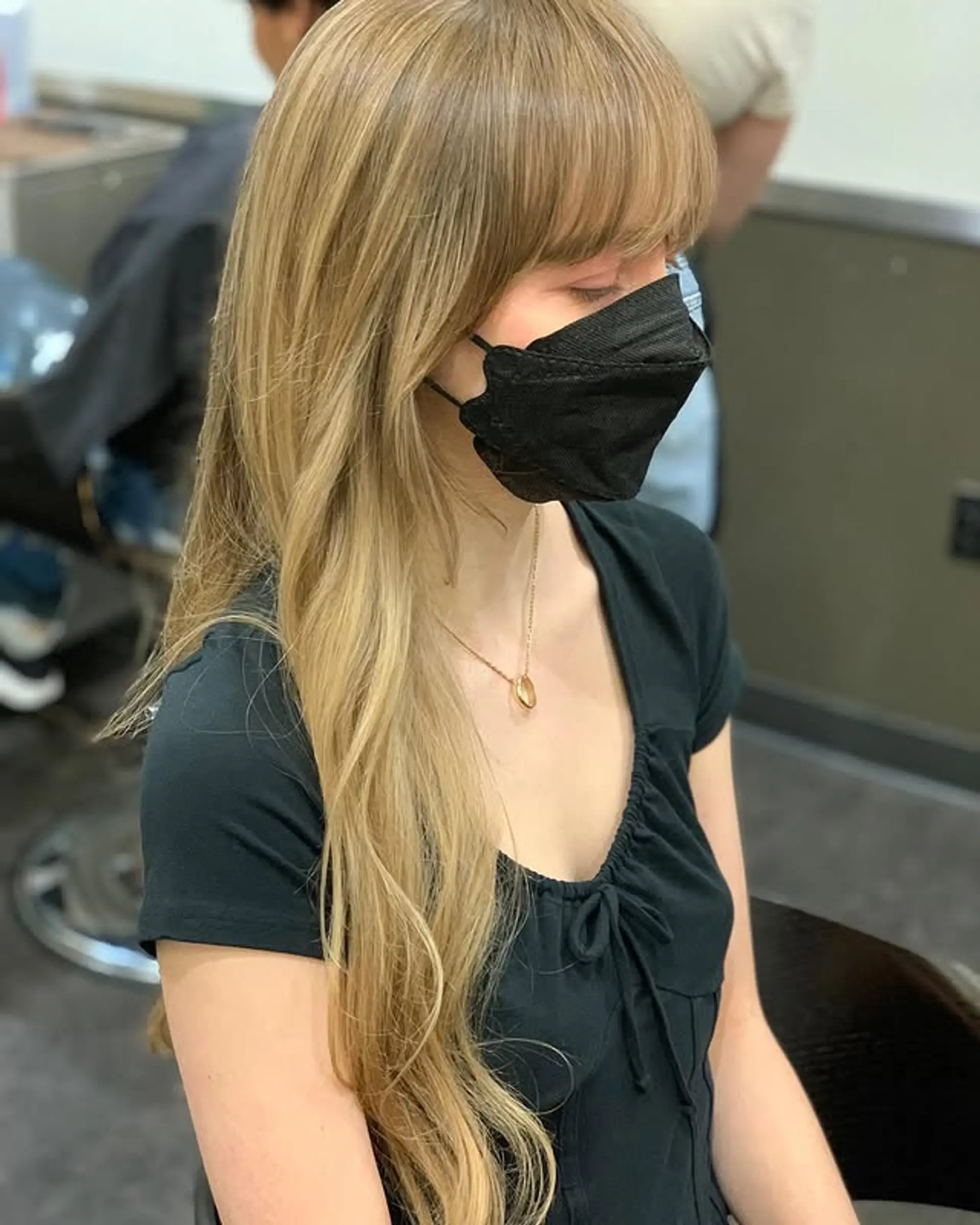 Long layered blonde hair styled with beachy waves and Bardot bangs. 1
