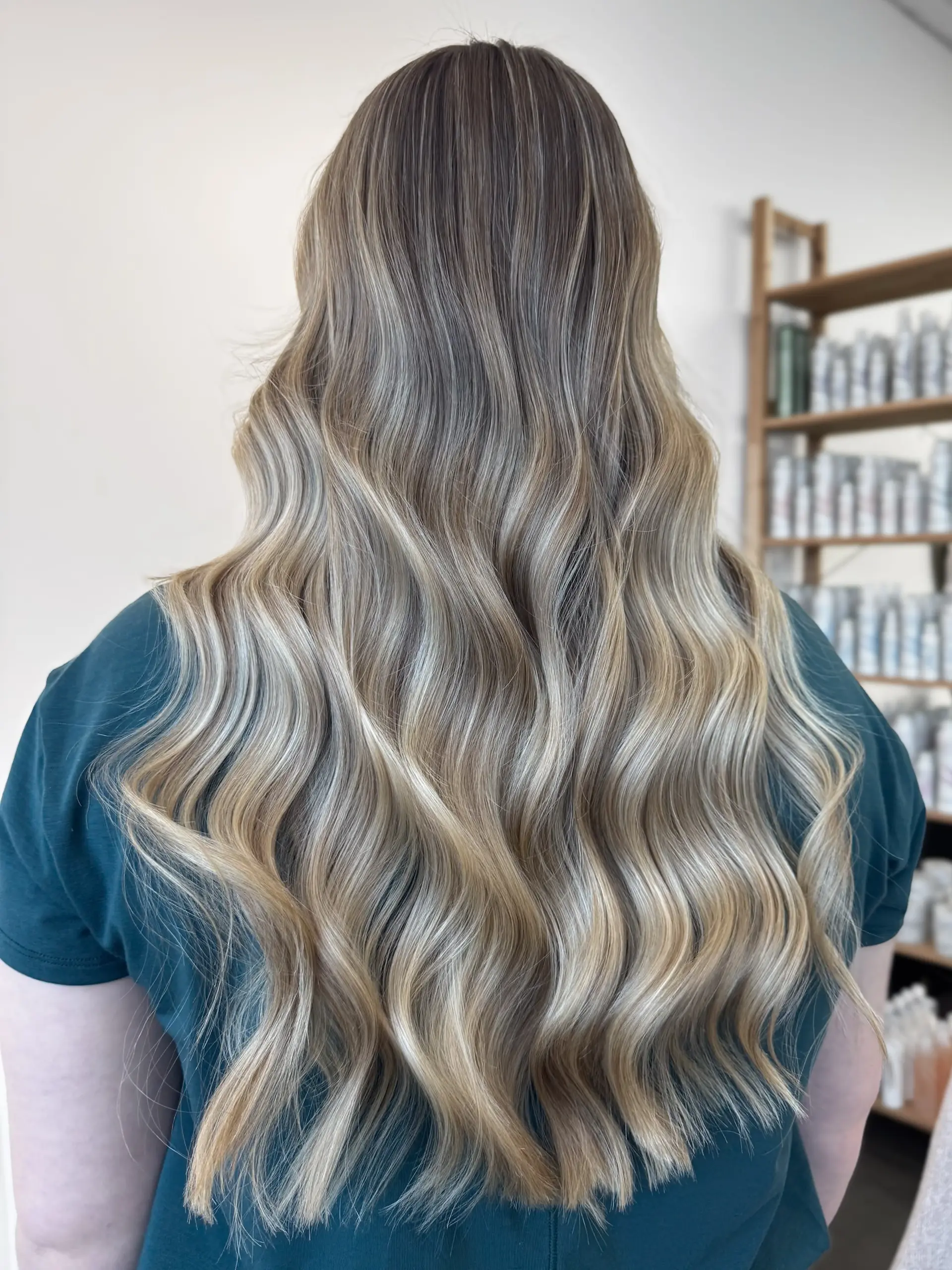 Long hair featuring a seamless dimensional blonde balayage styled into soft, fluid waves. 1