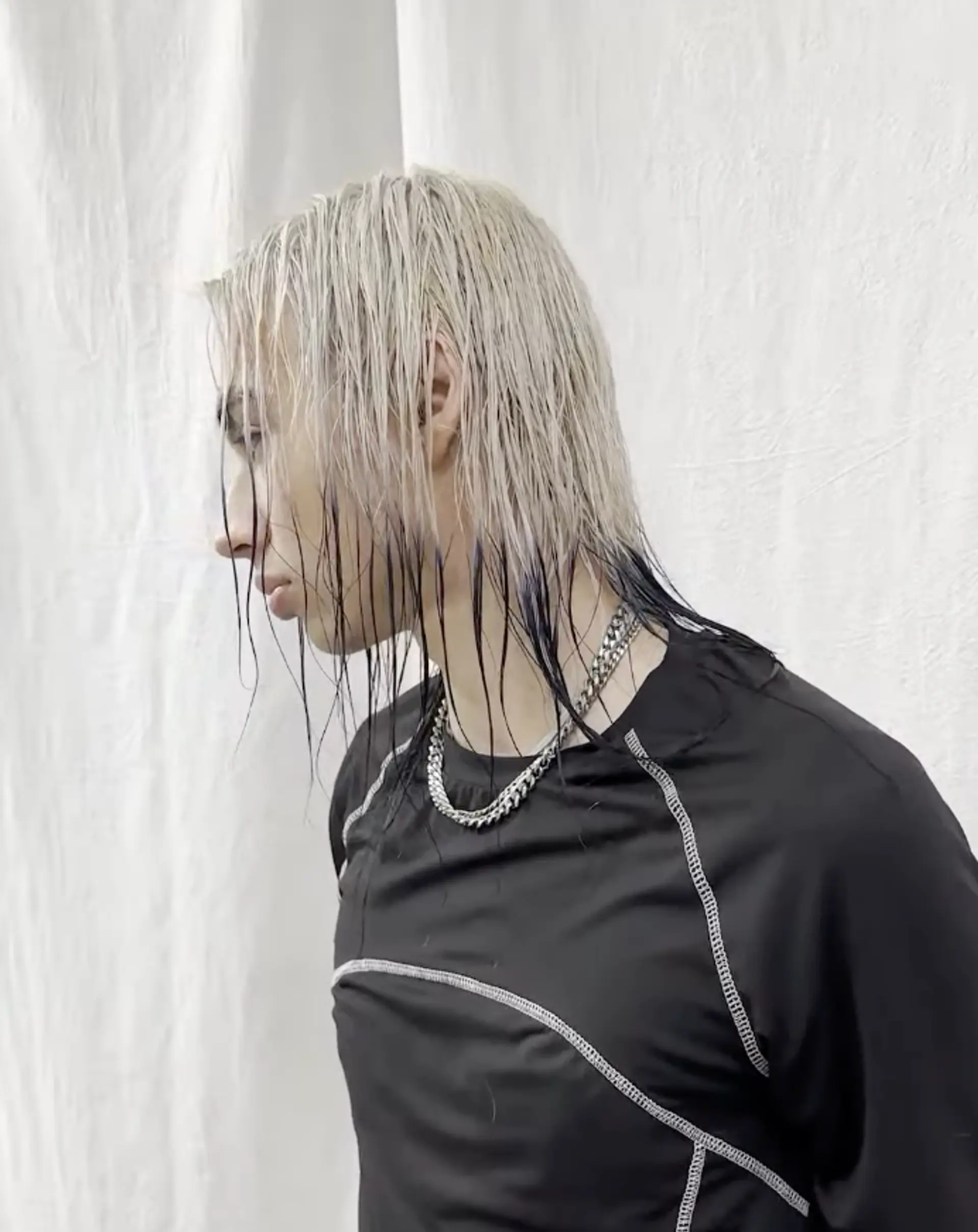 Medium-length, platinum blonde hair with black tips, layered and textured for an edgy, wet look style. 1