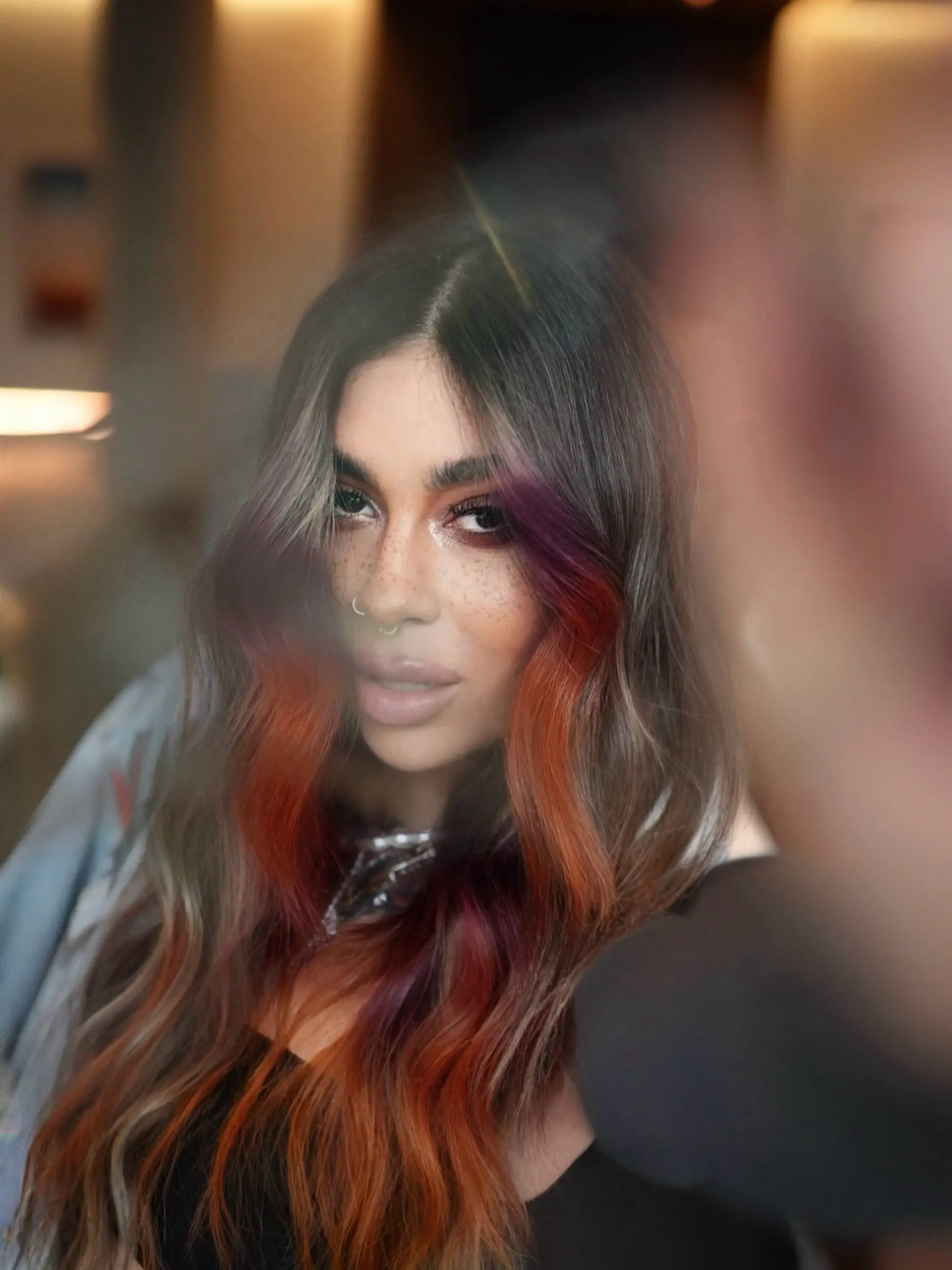 Long wavy brunette hair featuring vibrant sunset-toned face-framing accents in shades of orchid purple, coral, and vivid orange. 1