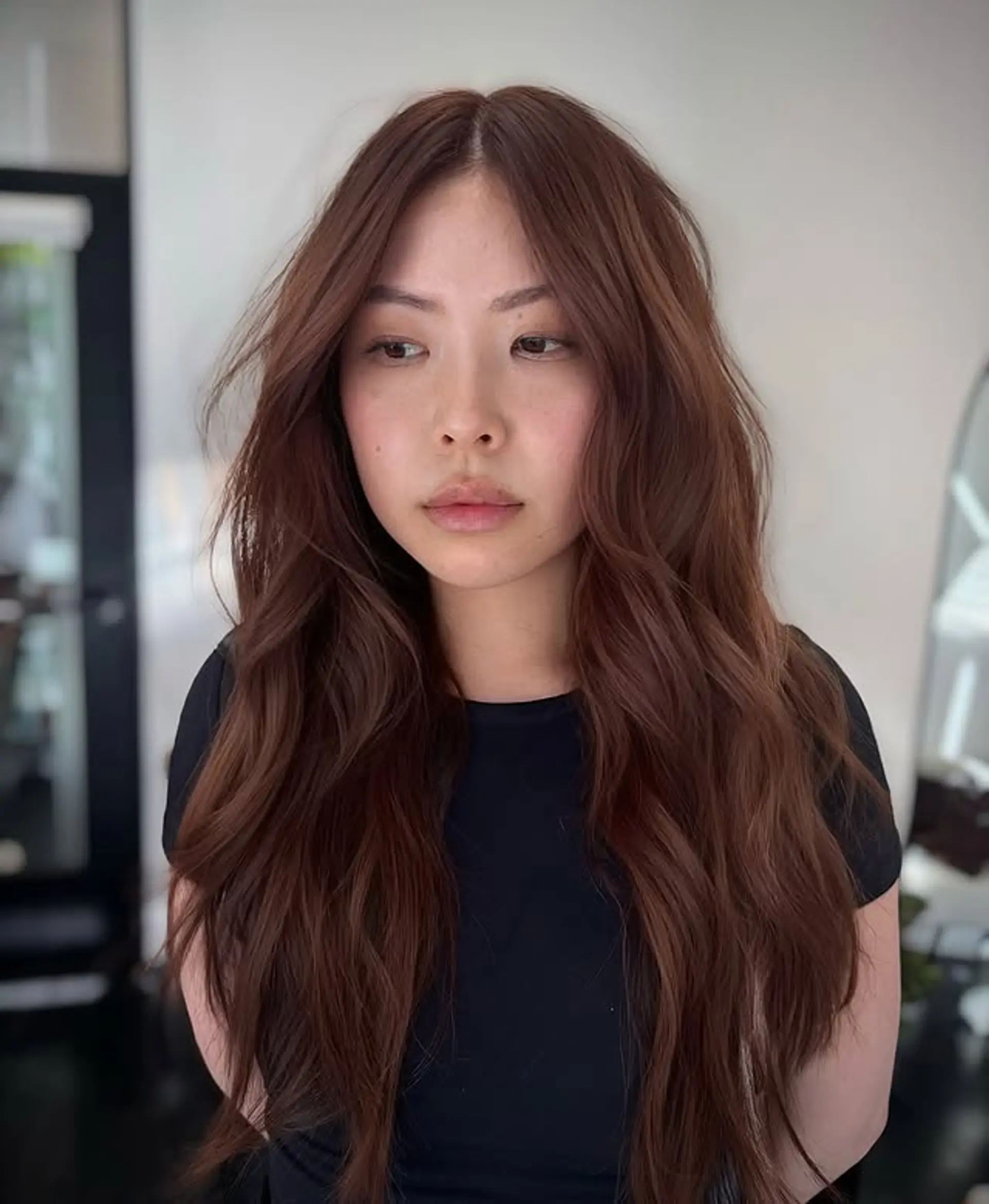 Long layered auburn hair with soft waves and a center part. 1