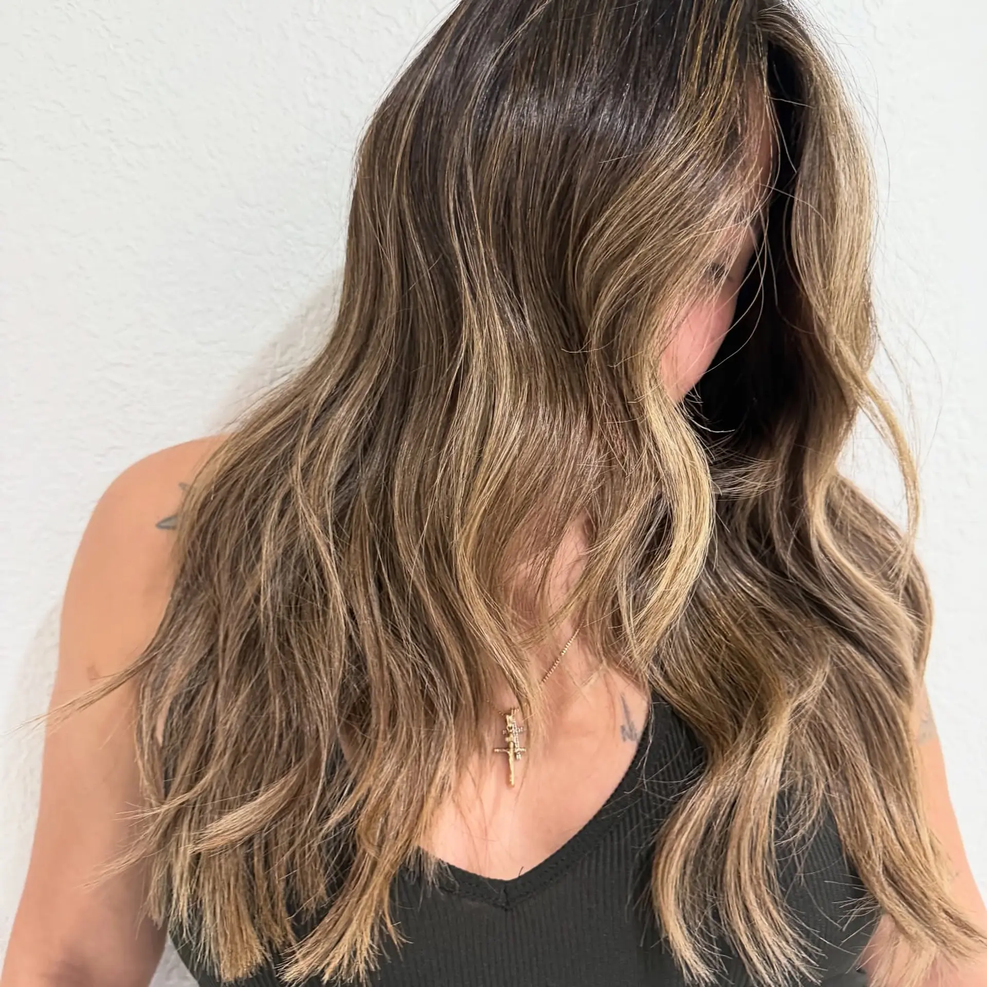 Long, flowing textured waves featuring a dimensional blend of beige and caramel balayage over a deep brunette base. 1
