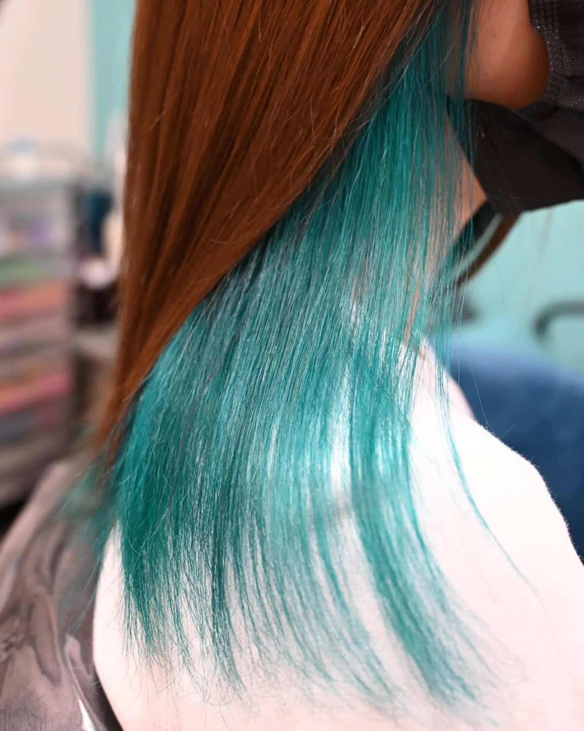 Straight warm brown hair styled to reveal a vibrant teal-turquoise peekaboo underlayer beneath. 1