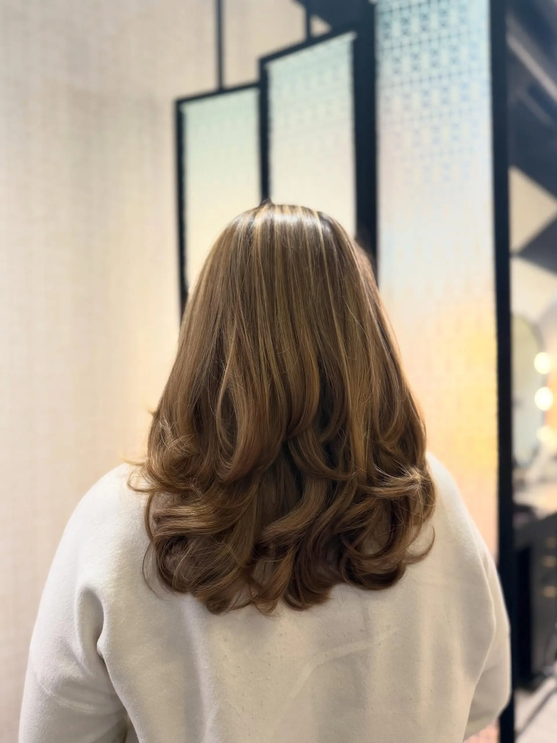 Long layered warm bronde hair styled with voluminous, curled-under ends. 1
