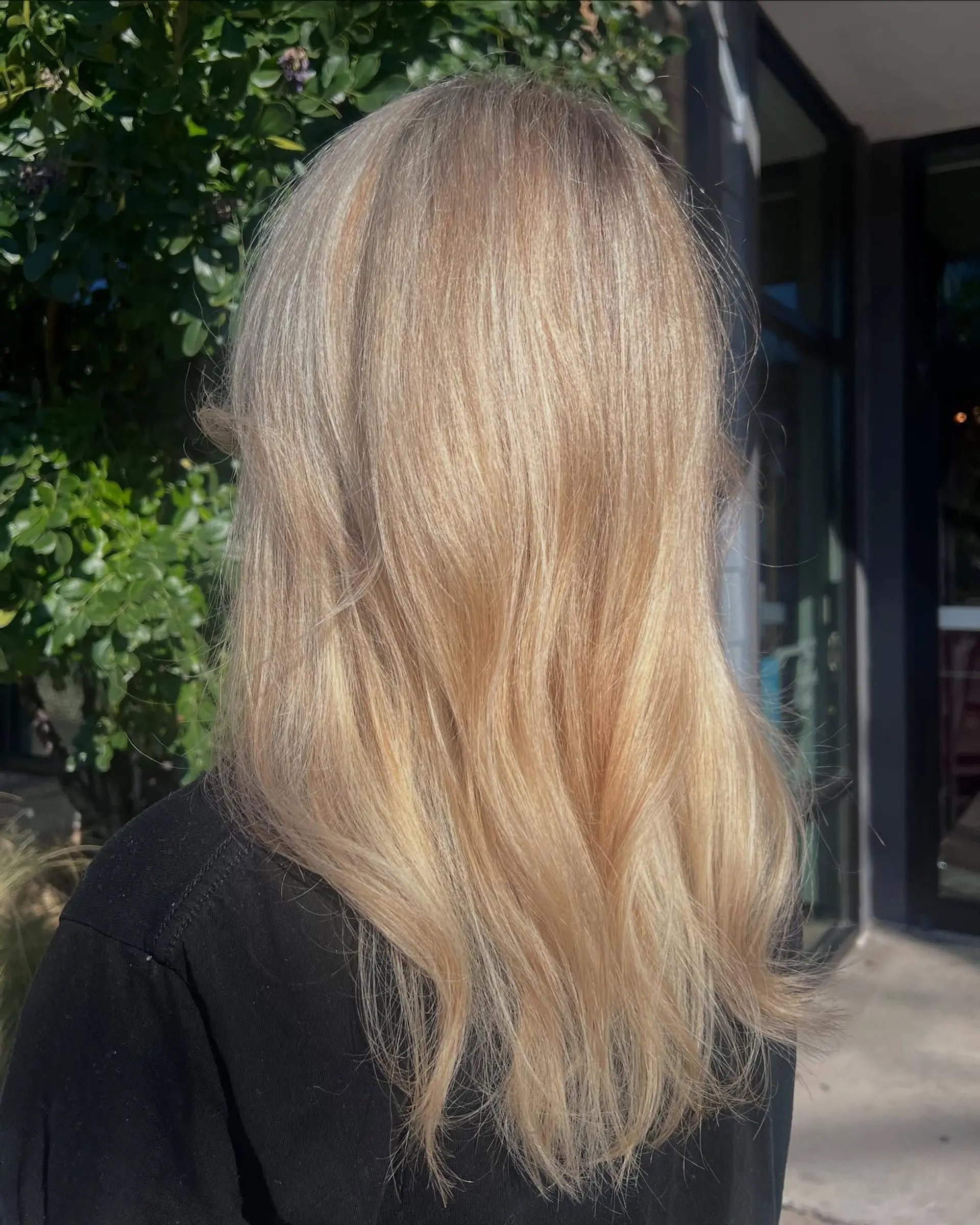 Long warm golden butter blonde hair styled with a smooth finish and soft, relaxed waves. 1