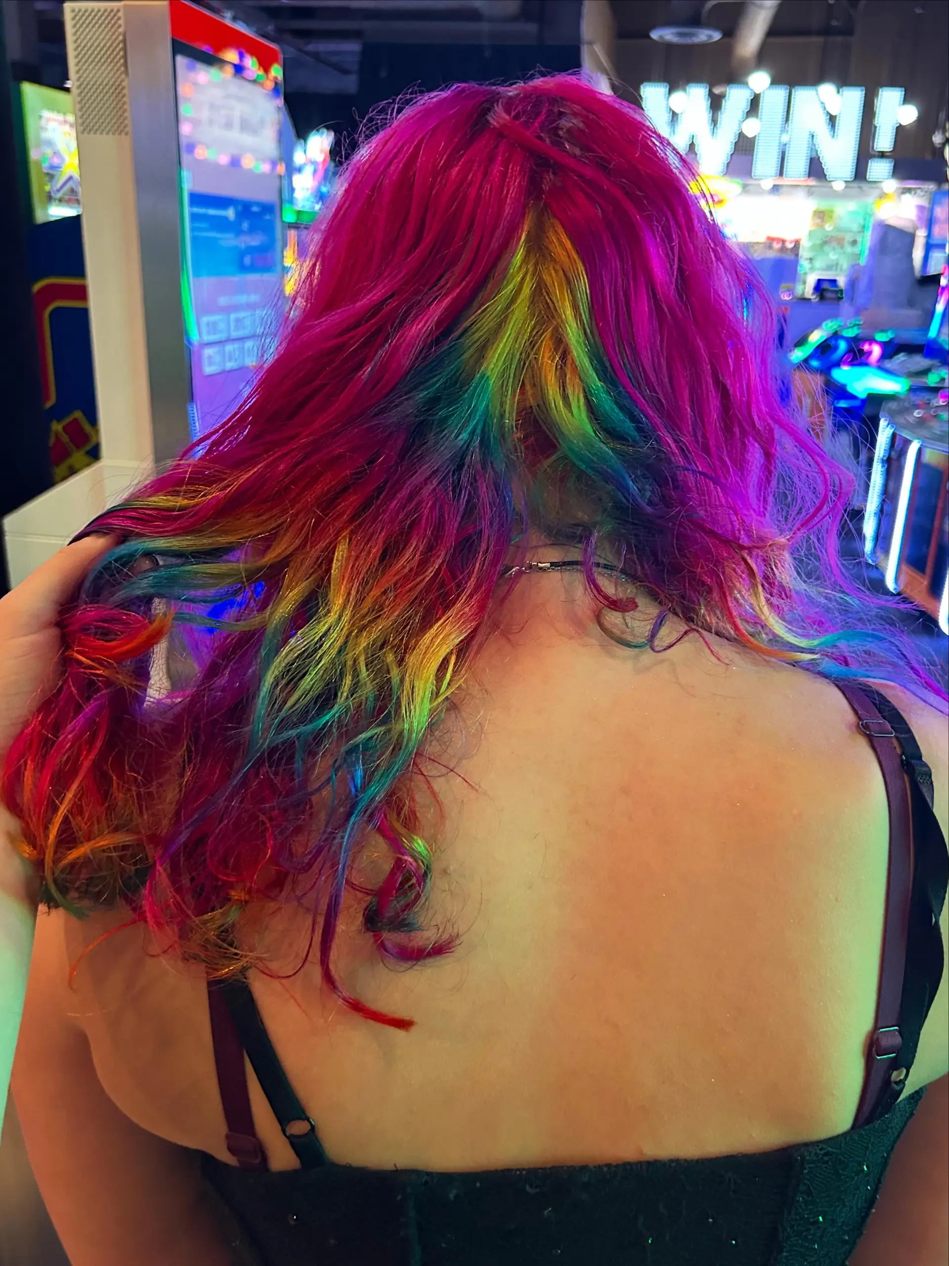 Vibrant magenta hair layered over a hidden rainbow under-section styled in textured waves. 1