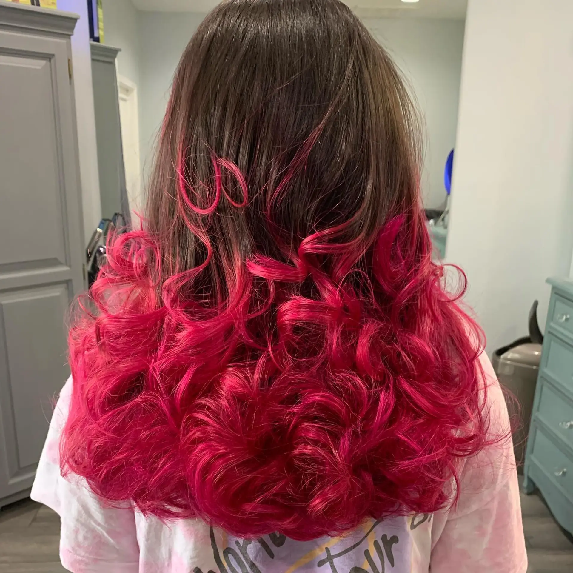 Brunette hair transitioning into vivid fuchsia ends styled with voluminous spiral curls. 1