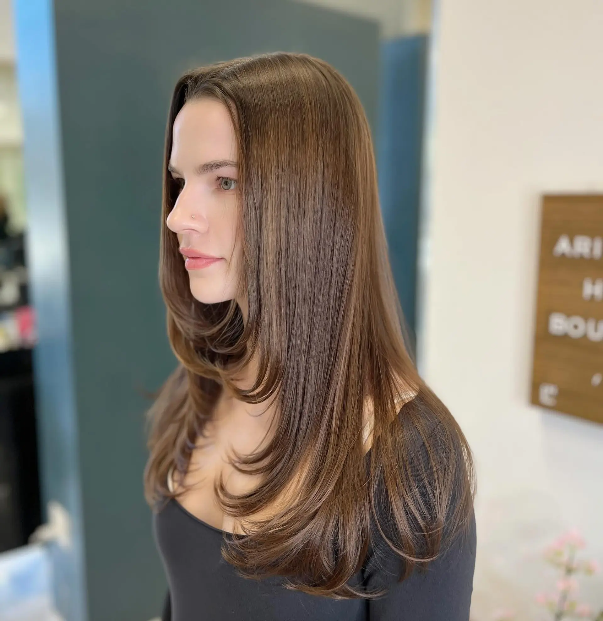 A sleek, long layered haircut featuring smooth, feathered face-framing layers styled softly inward. 1