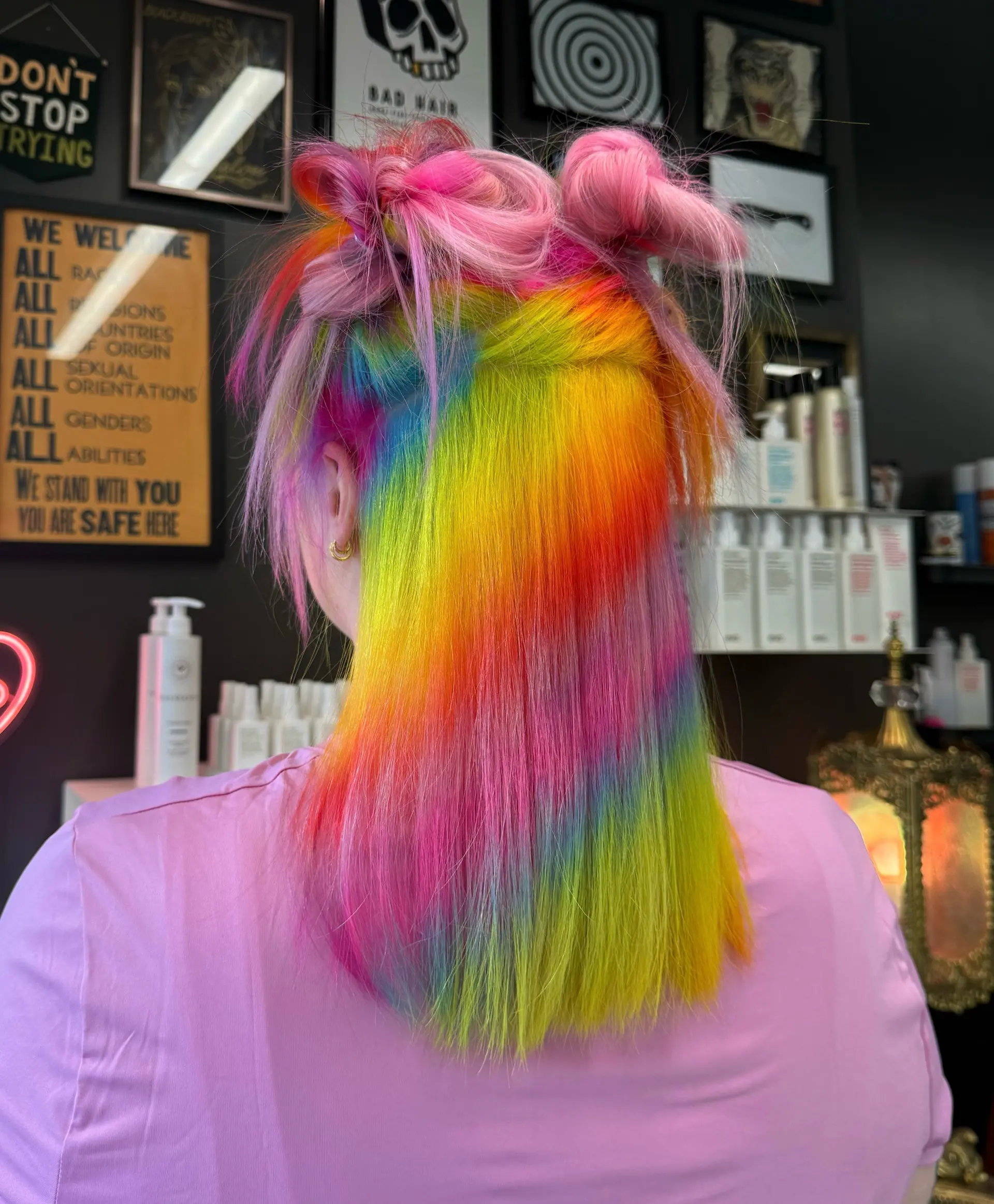 Vibrant rainbow colored hair styled straight through the back with pastel pink space buns at the top. 1