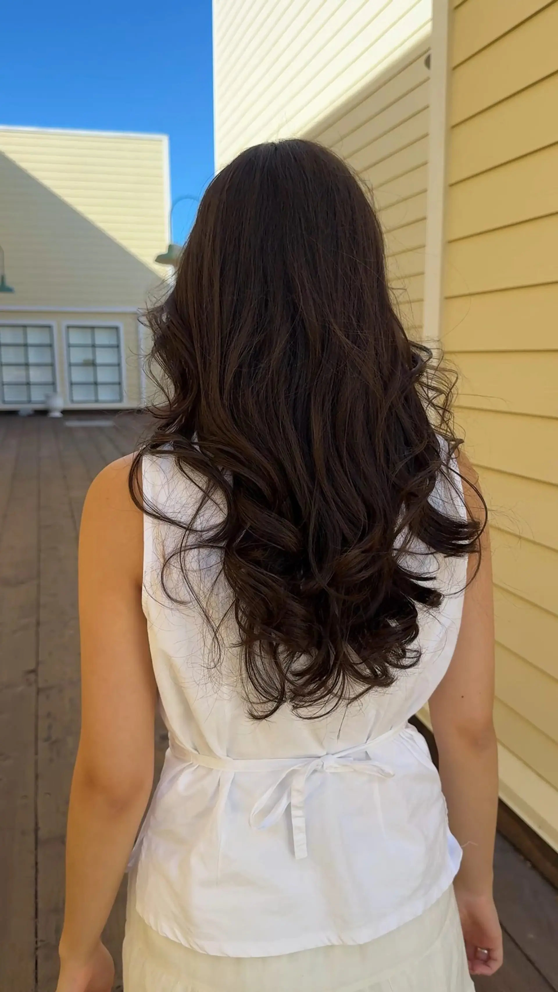 Long dark brown hair cut with soft cascading layers and styled into bouncy, voluminous curls at the ends. 1