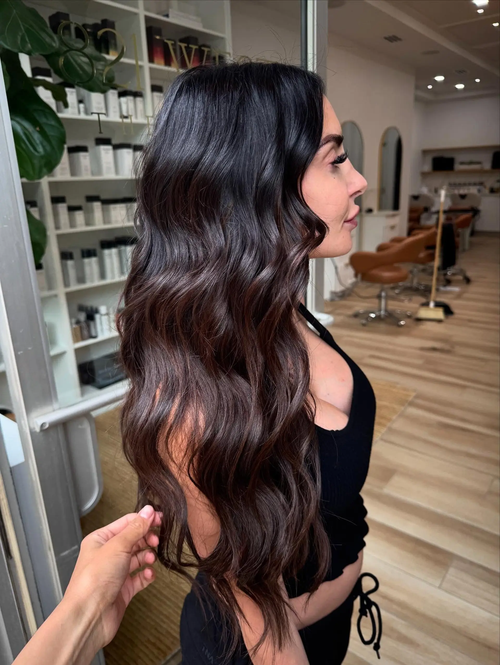 Extra-long rich dark chocolate brown hair styled with soft, cascading waves and high shine. 1