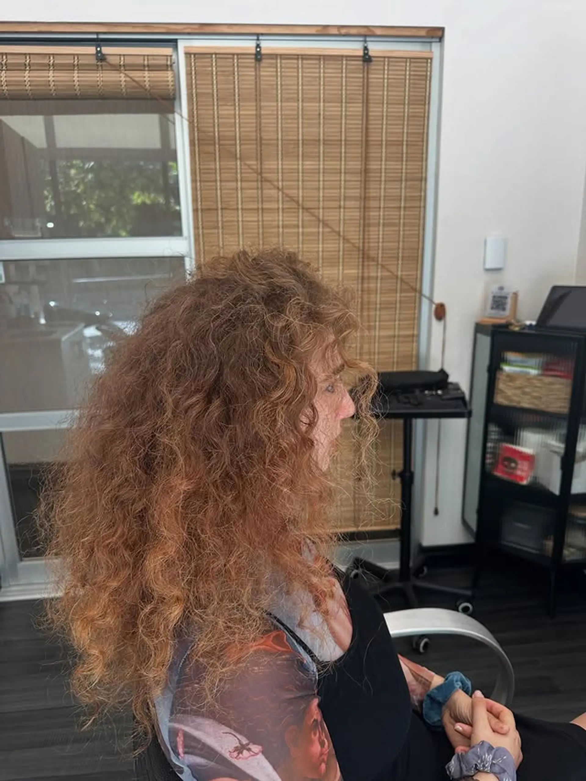 A voluminous and textured long curly hairstyle, dyed in a copper tone. 1