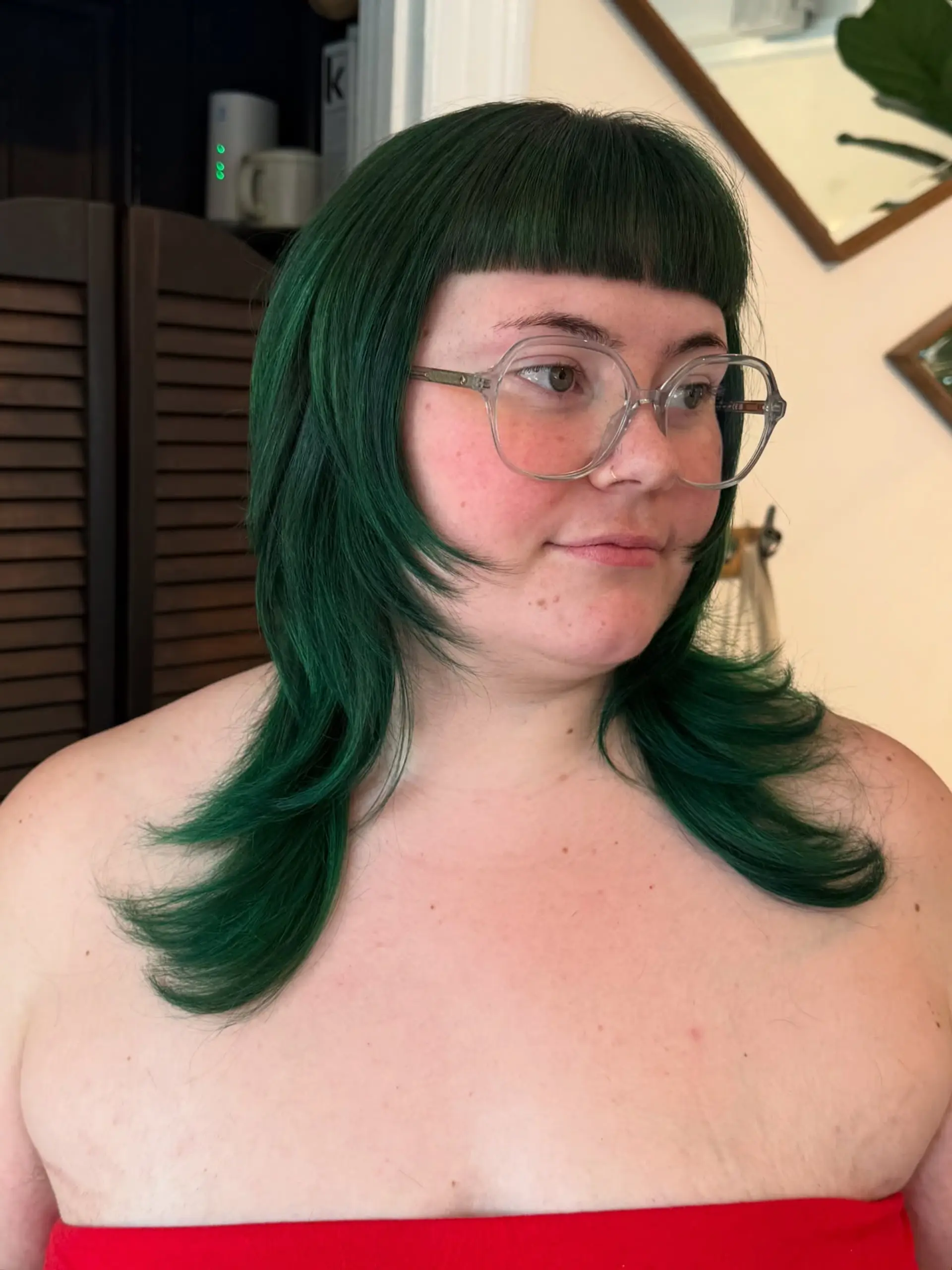 Vibrant emerald green layered cut featuring blunt micro bangs and sharp, stepped face-framing layers with flared ends. 1