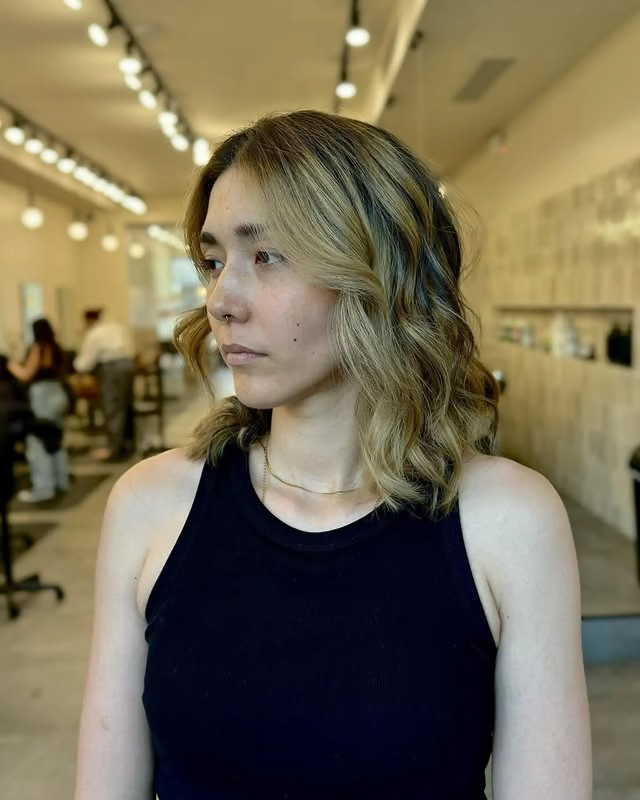 A stylish lob with wavy texture, blonde balayage and face-framing curtain bangs.