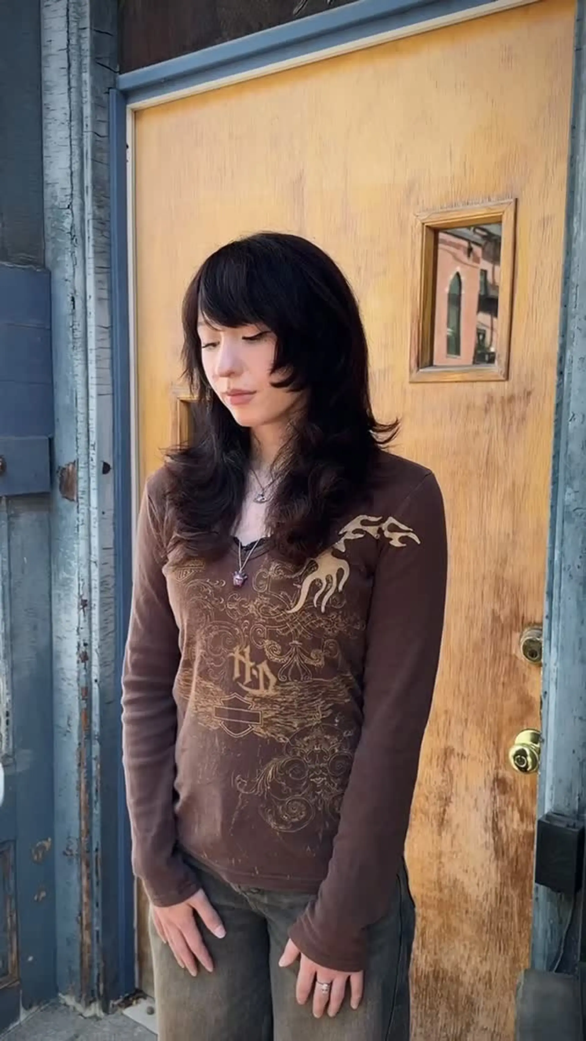 A textured mid-length shag haircut with blunt face-framing cheekbone layers, rounded full fringe bangs, and soft flicked ends. 1