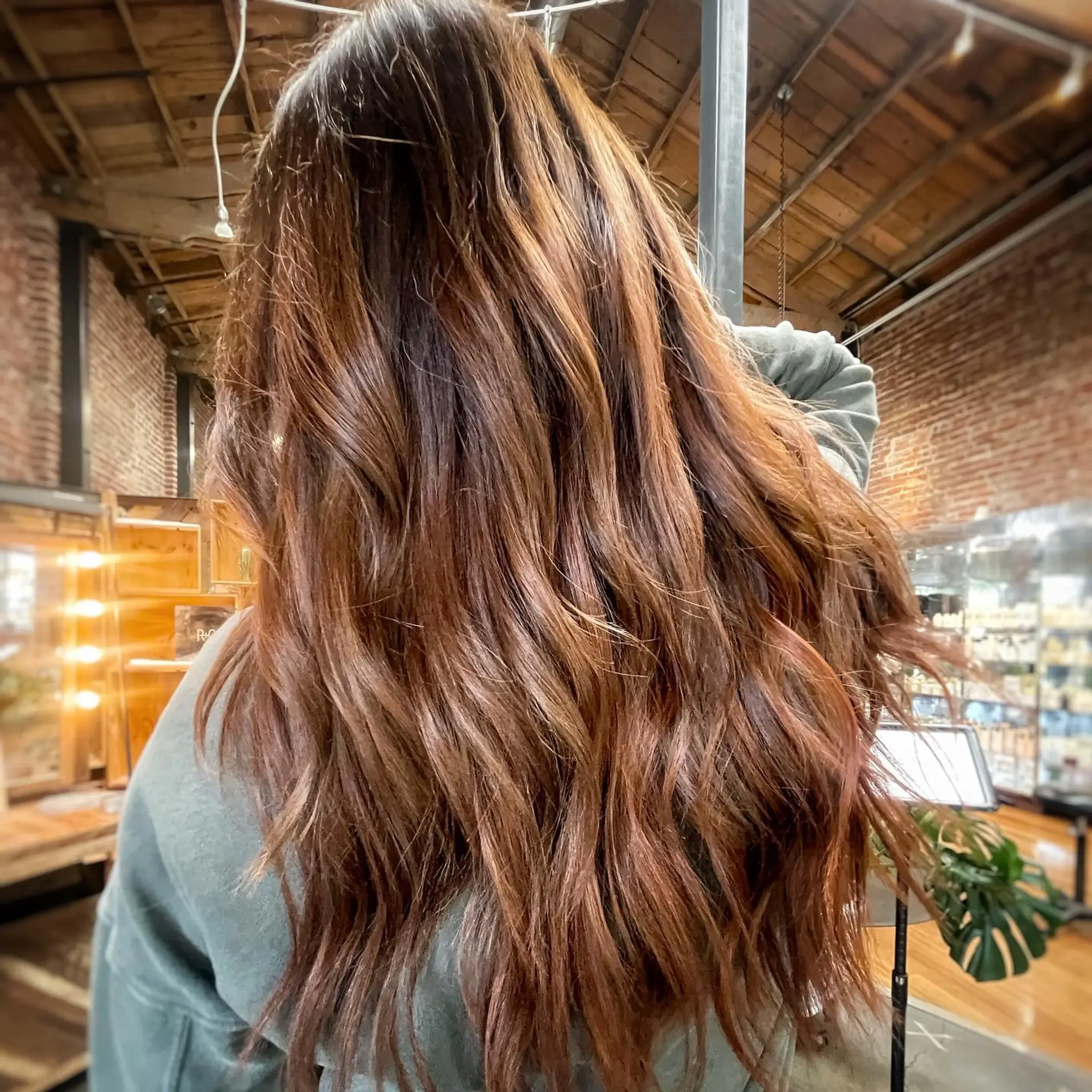 Long, flowing auburn-brown hair styled in textured, effortless waves with subtle warm highlights. 1