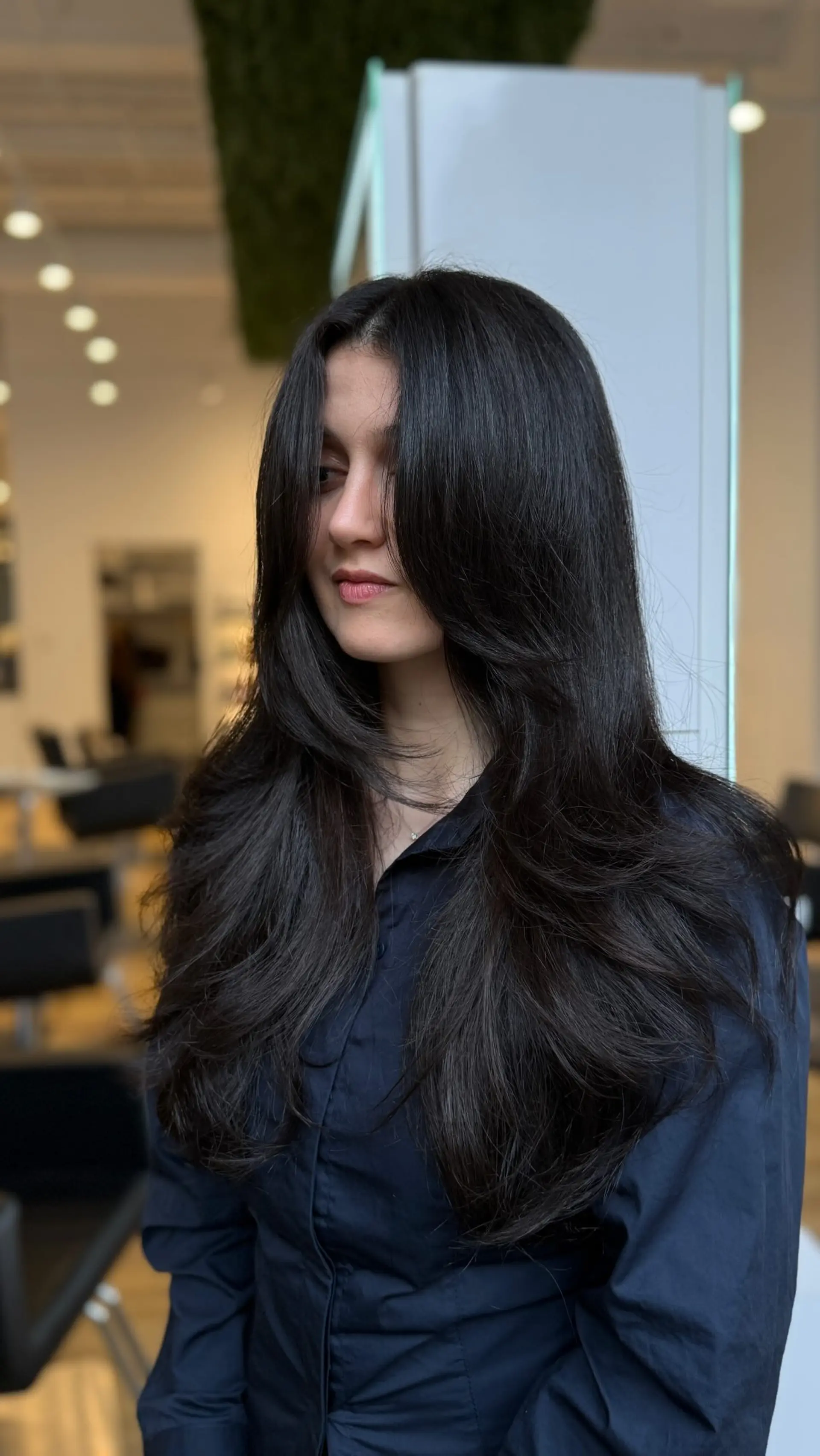 Long, dark layered hairstyle with soft face-framing curtain bangs and a bouncy blowout. 1