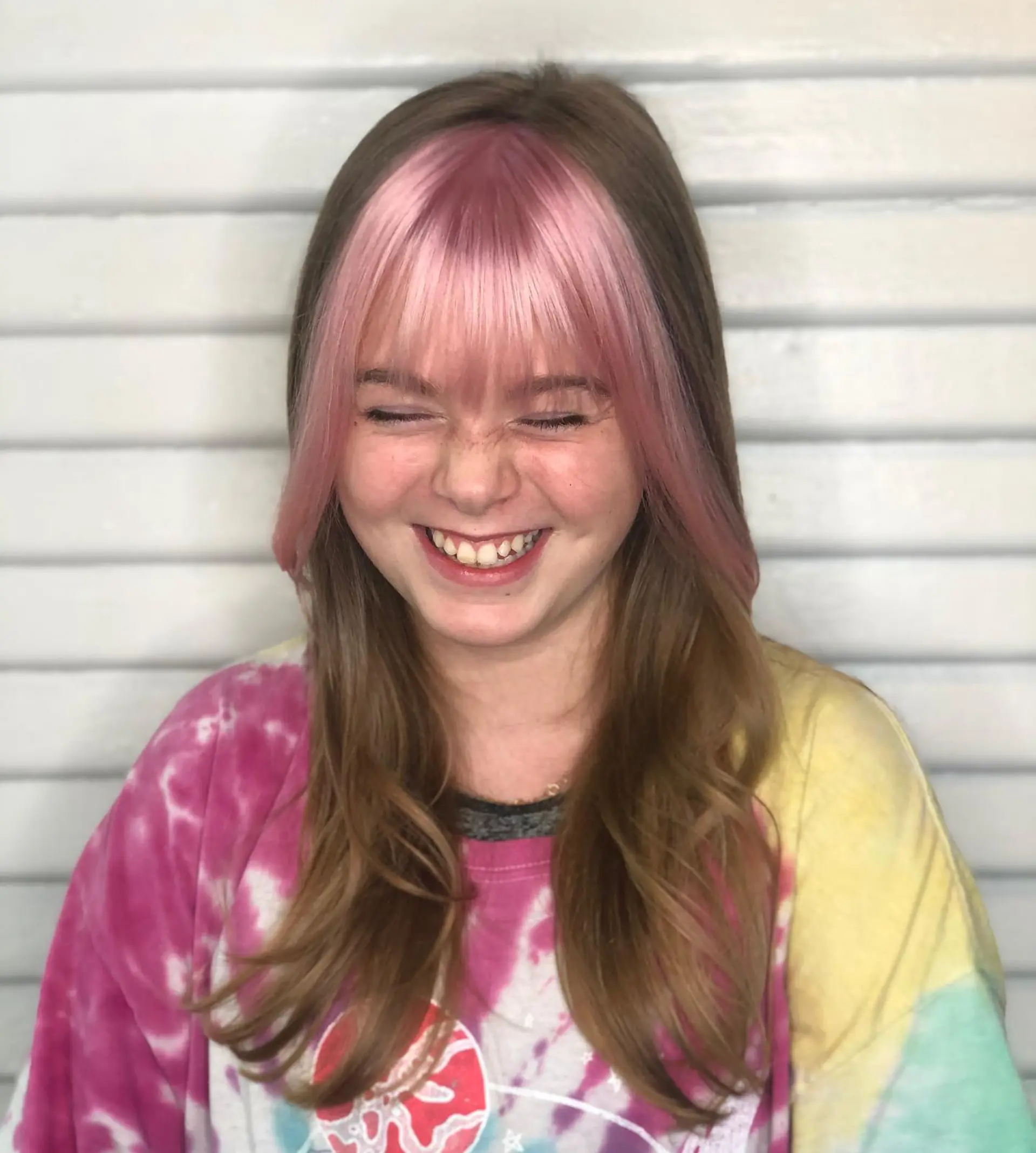 Medium-length light brown hair styled with soft waves and contrasting pastel pink straight bangs with face-framing strands. 1