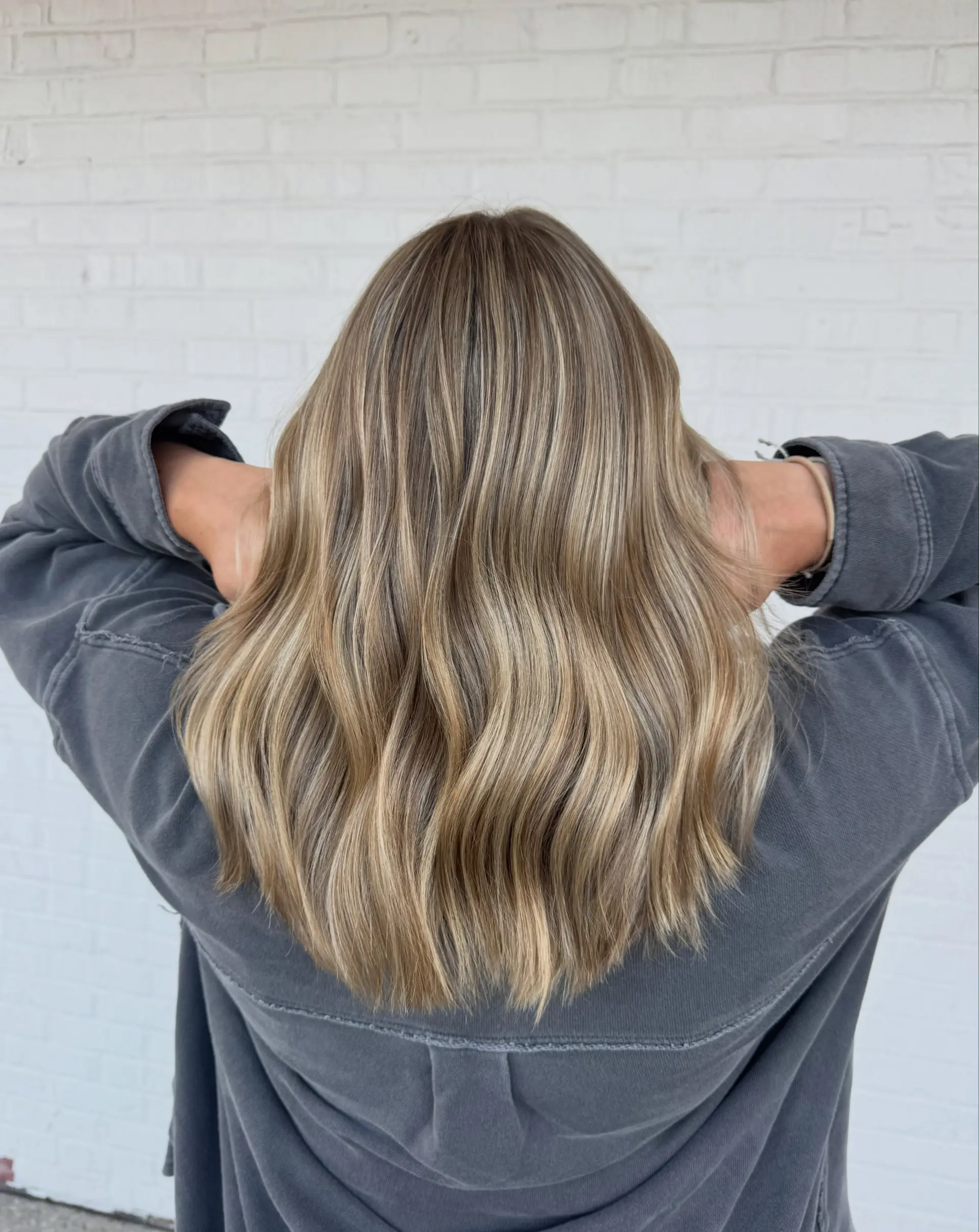 Medium-length vanilla blonde hair featuring blended full highlights and soft, subtle waves. 1