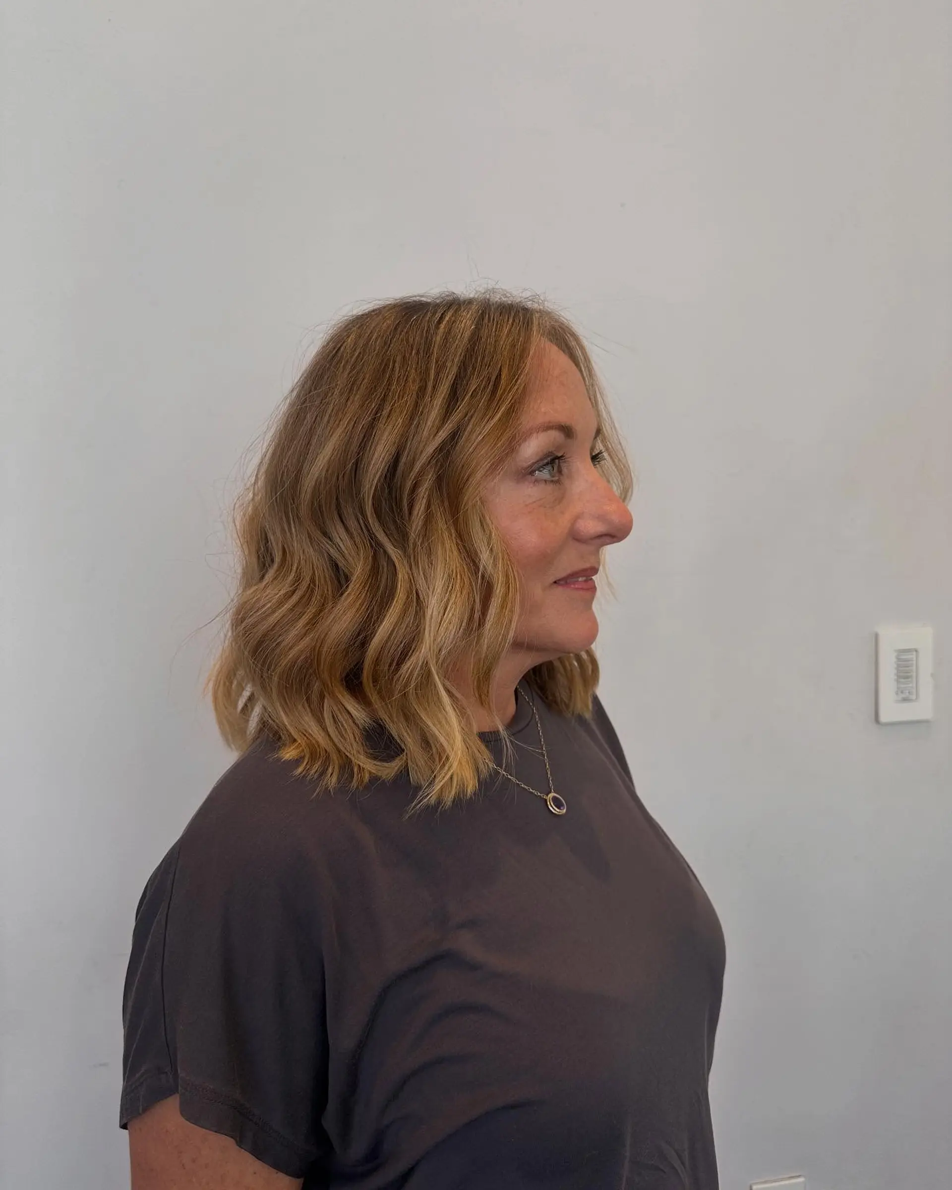 A shoulder-length blunt one-length lob haircut styled into loose, undone waves with multi-dimensional warm blonde tones. 1