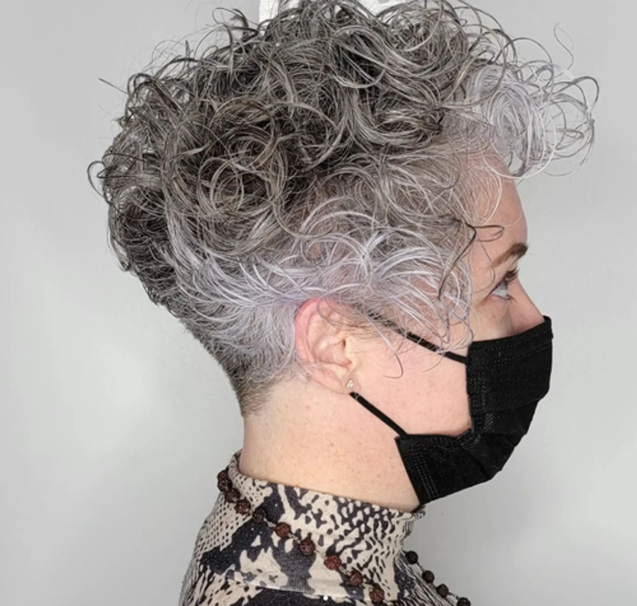 Short curly hairstyle with defined silver curls, closely cropped sides, and a frosted appearance with a seamless fade.