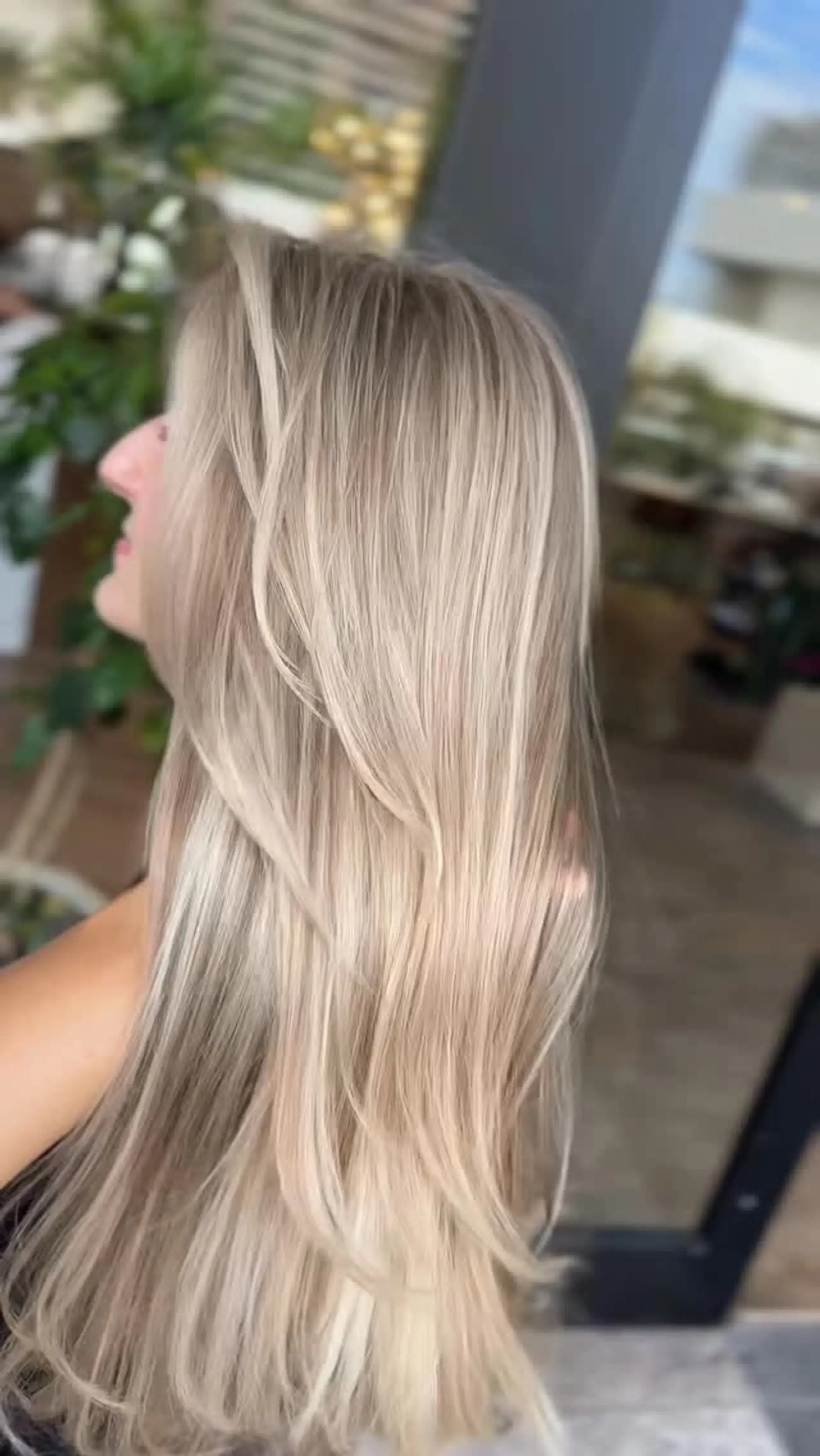 Long ash blonde hair featuring seamless multi-tonal highlights, shaped with soft face-framing layers and styled into a sleek blowout. 1