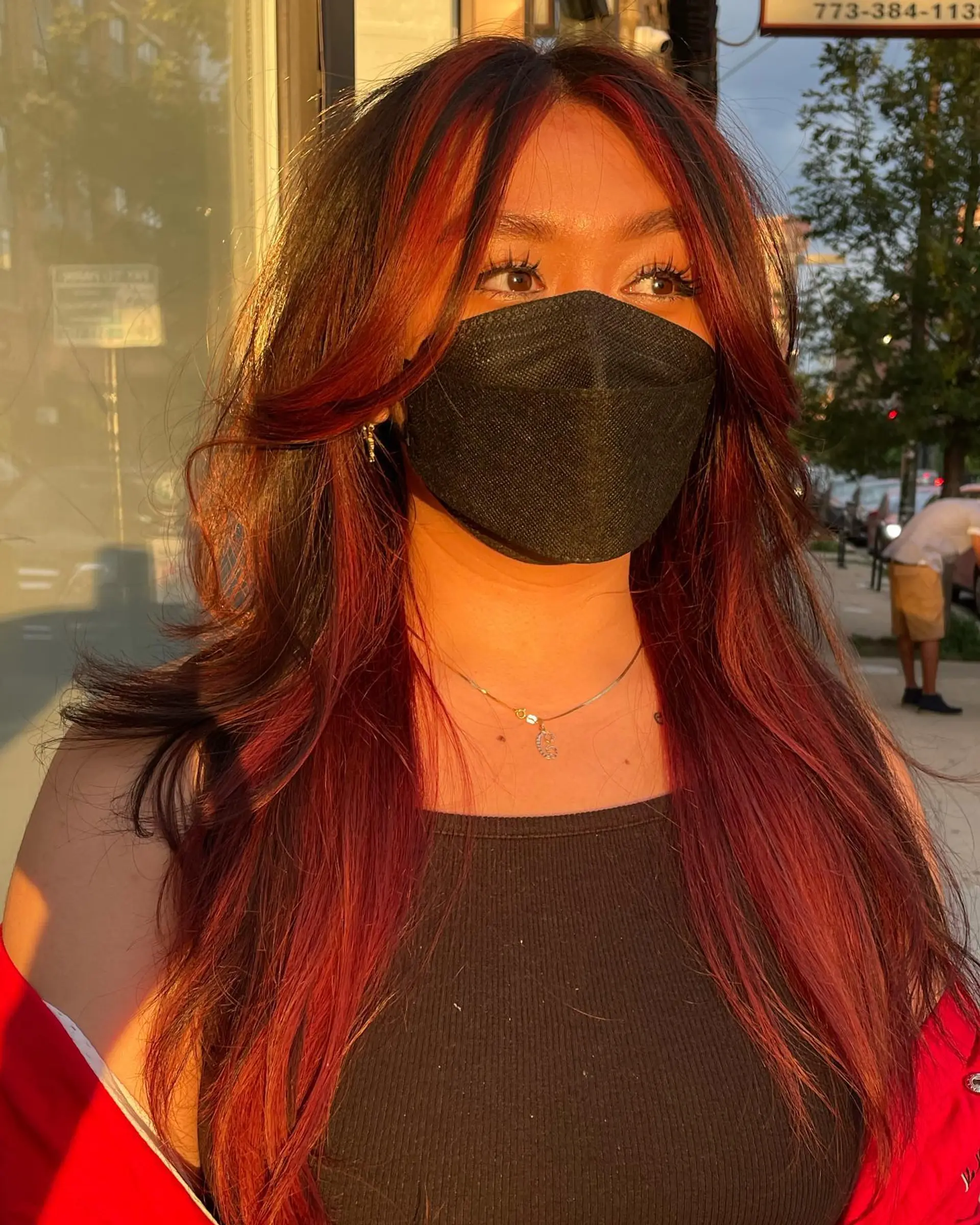 Long, face-framing layers with red money piece highlights. 2