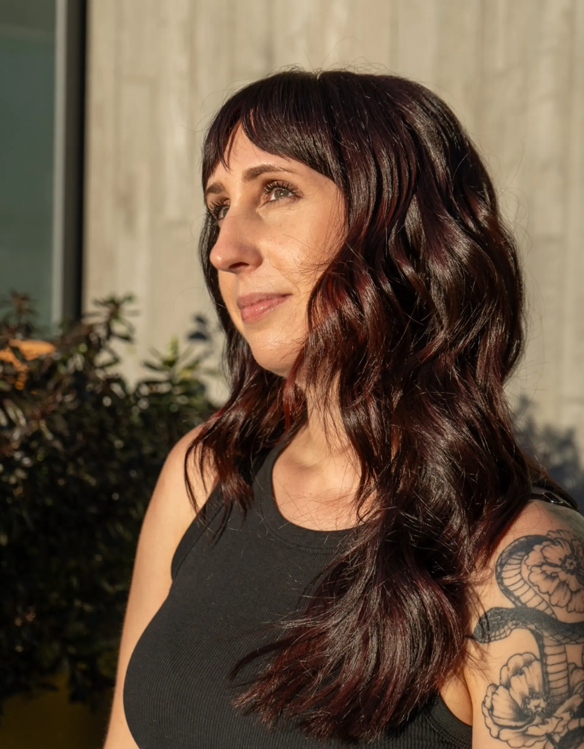 Long wavy hair in a rich dark cherry cola shade with full piecey bangs. 1