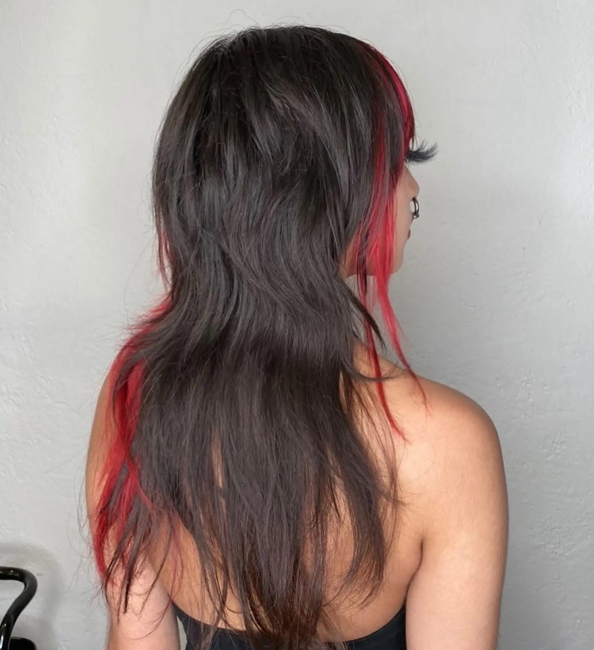 A heavily layered shaggy mullet cut in dark brown with contrasting vivid red face-framing streaks and peekaboo sections. 1