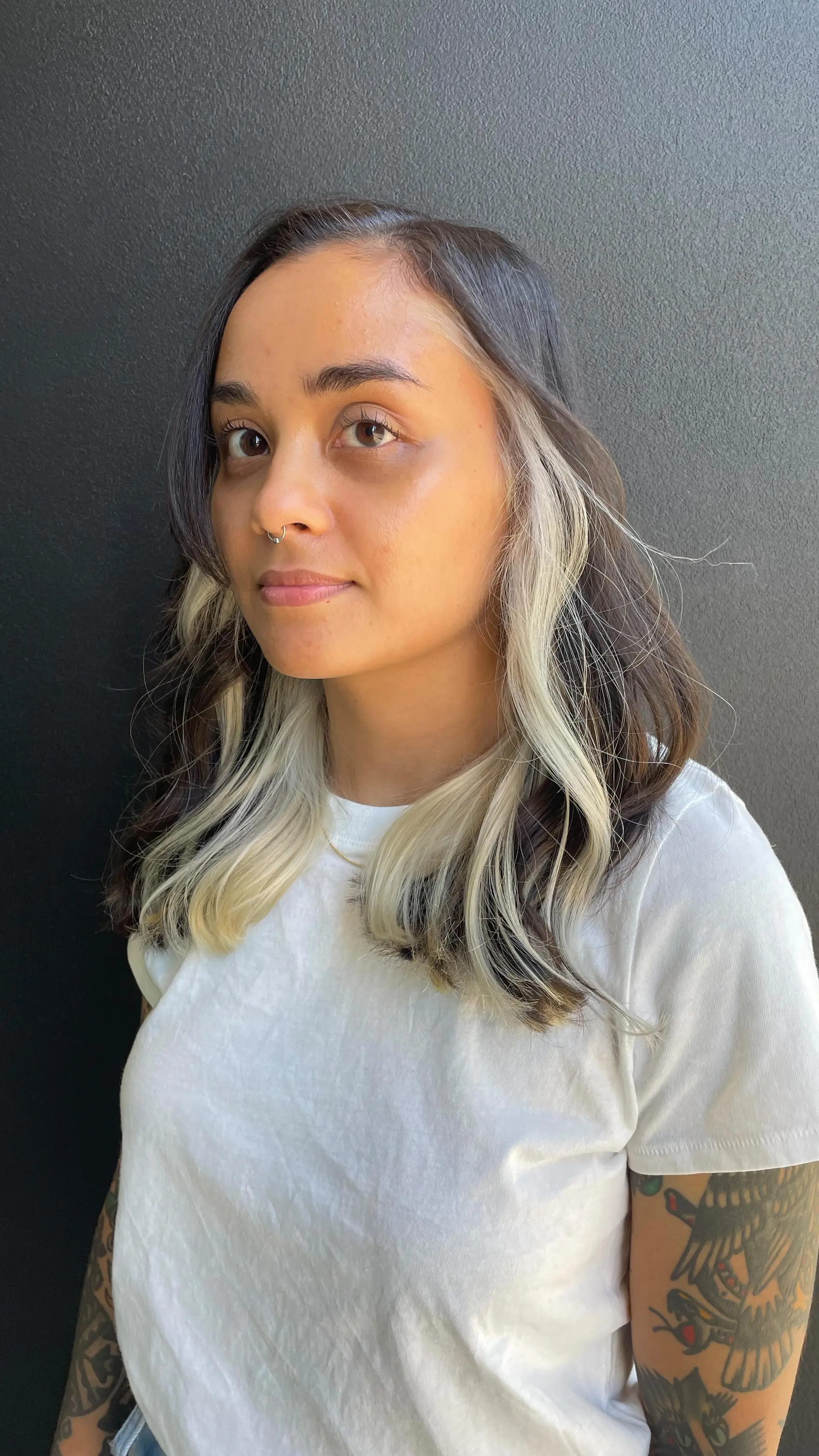 Medium-length dark brown hair styled in loose waves, accented by high-contrast platinum blonde face-framing money pieces. 1