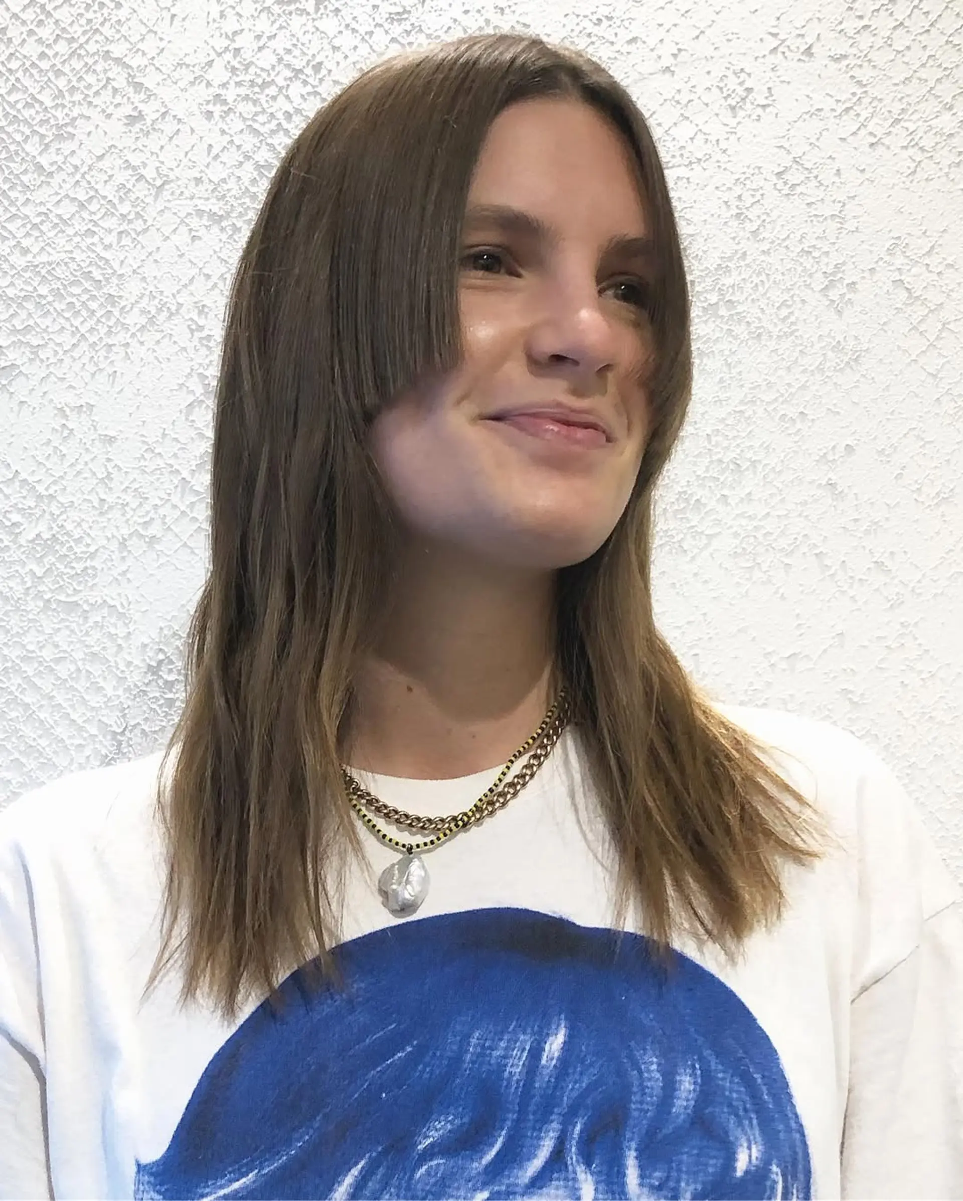 Medium-length light brown hair with straight texture and curtain bangs. It features face-framing layers and a relaxed, natural finish. 1