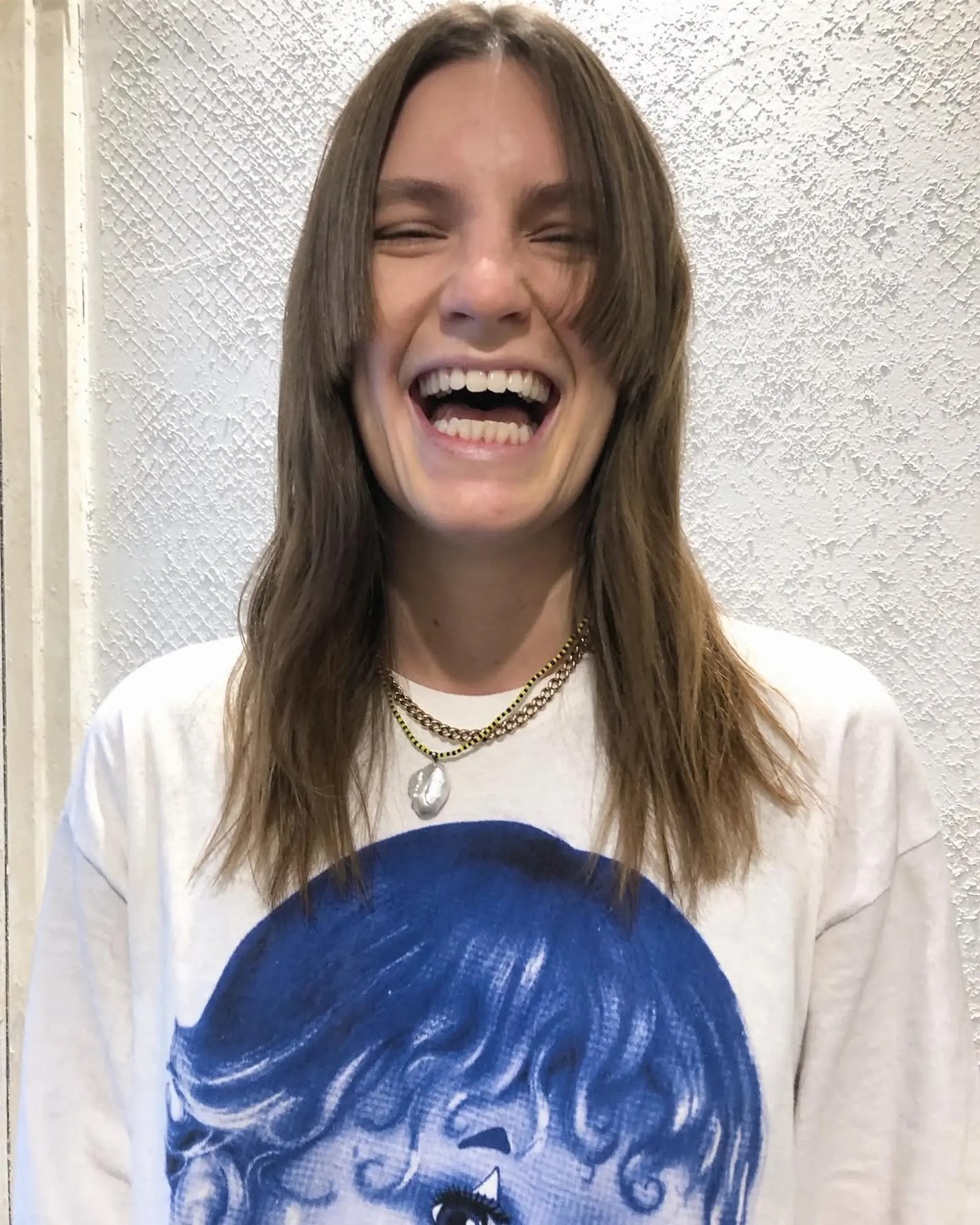 Medium-length light brown hair with straight texture and curtain bangs. It features face-framing layers and a relaxed, natural finish. 2