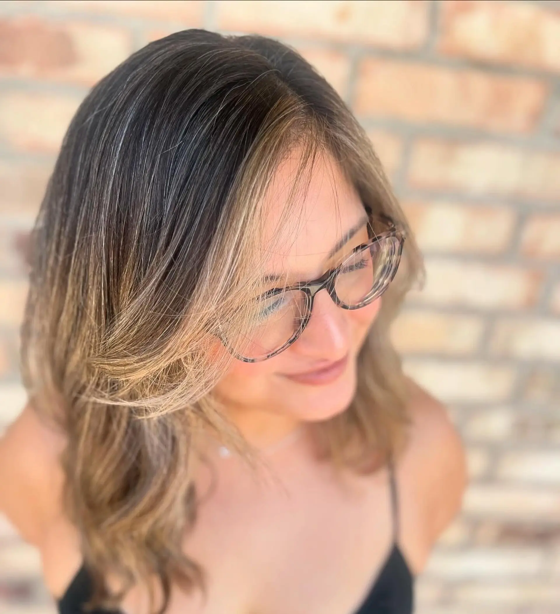 Medium-length brunette hair elevated with warm honey blonde balayage highlights and face-framing fringe styled in loose, soft waves. 1
