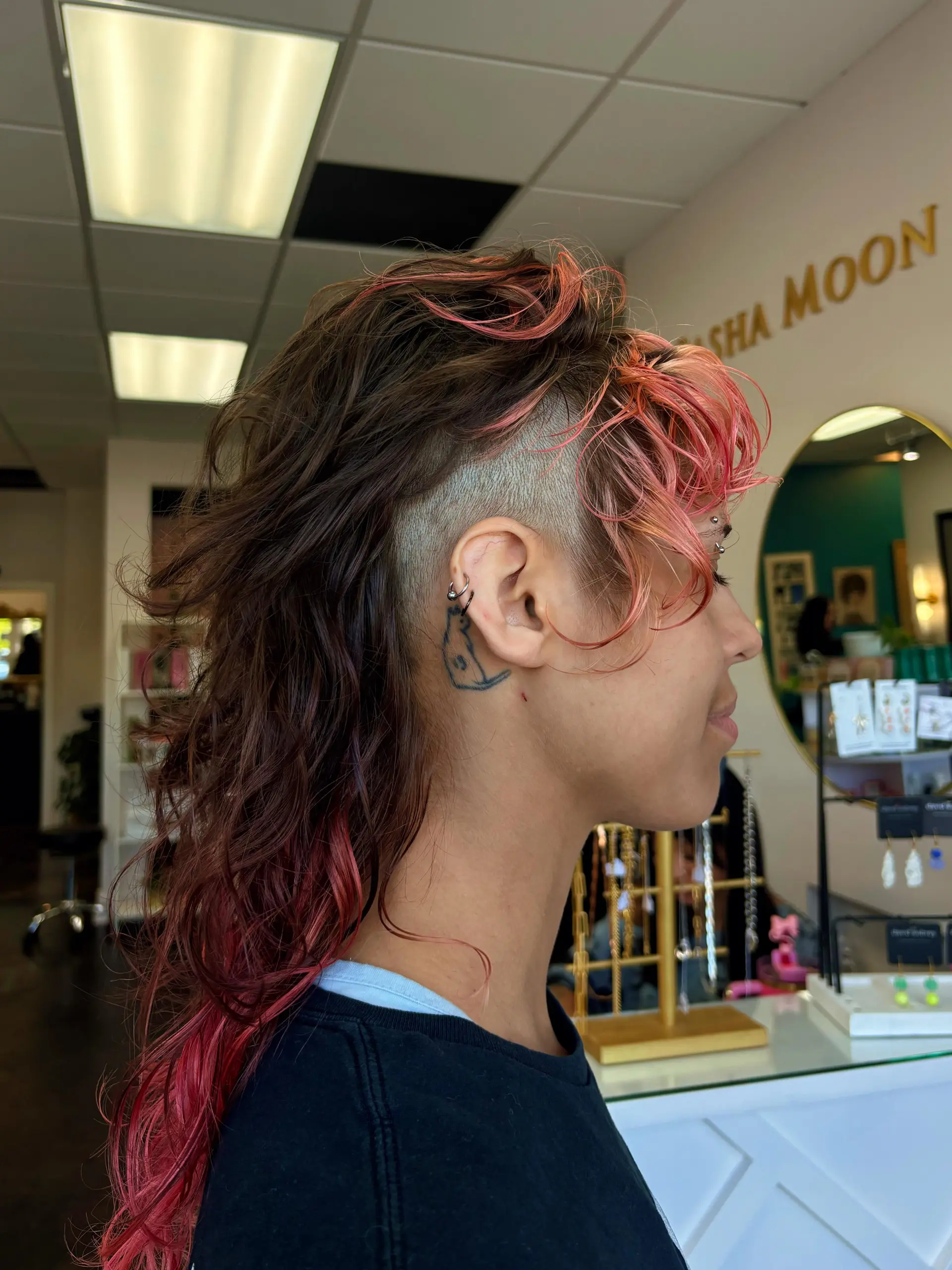 Edgy textured mullet with shaved undercut sides, tousled wavy volume on top, and vibrant pink accents through the fringe and ends. 1