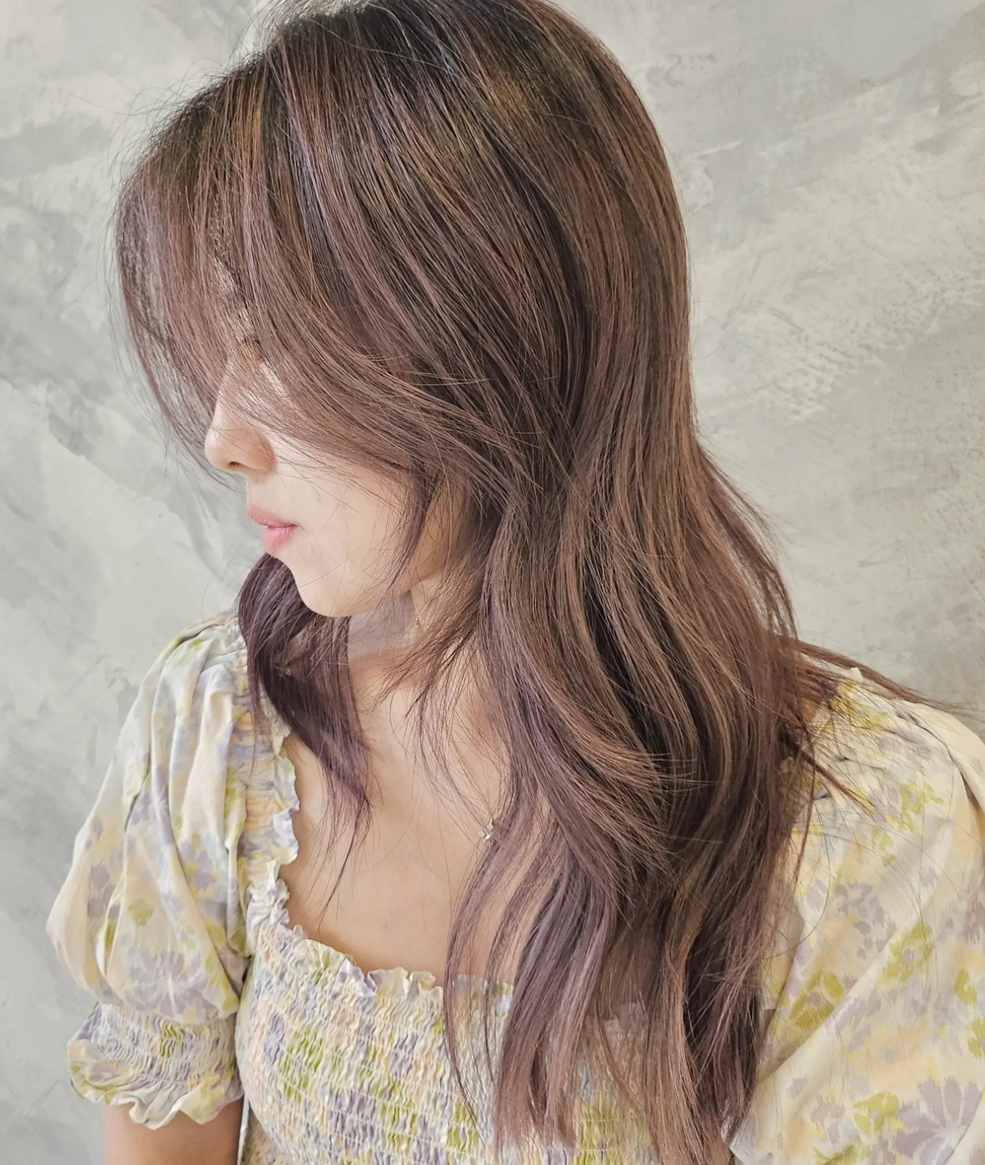 Long wavy hair styled with soft curtain bangs and subtle ash pink and purple balayage highlights. 1