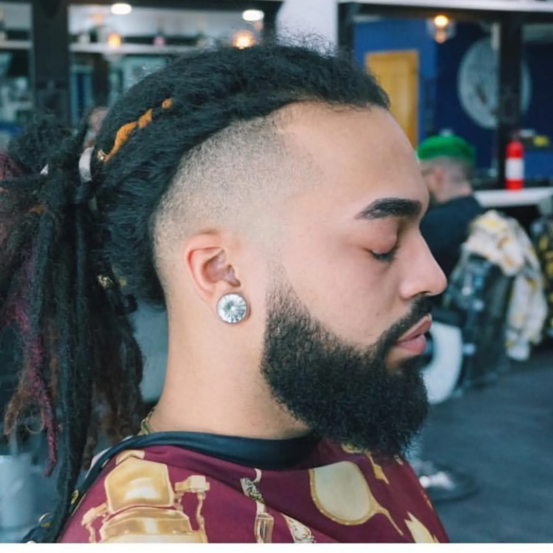 Long dreadlocks pulled back with a clean skin fade undercut and a sculpted, neatly lined beard. 1
