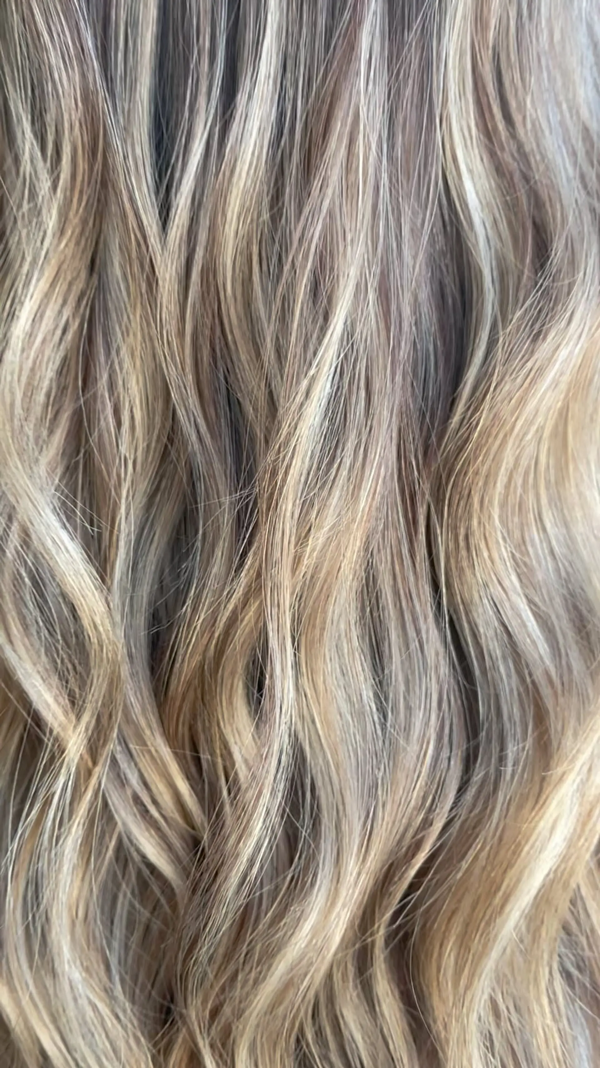 Dimensional blonde highlighted hair styled into soft, flowing waves. 1